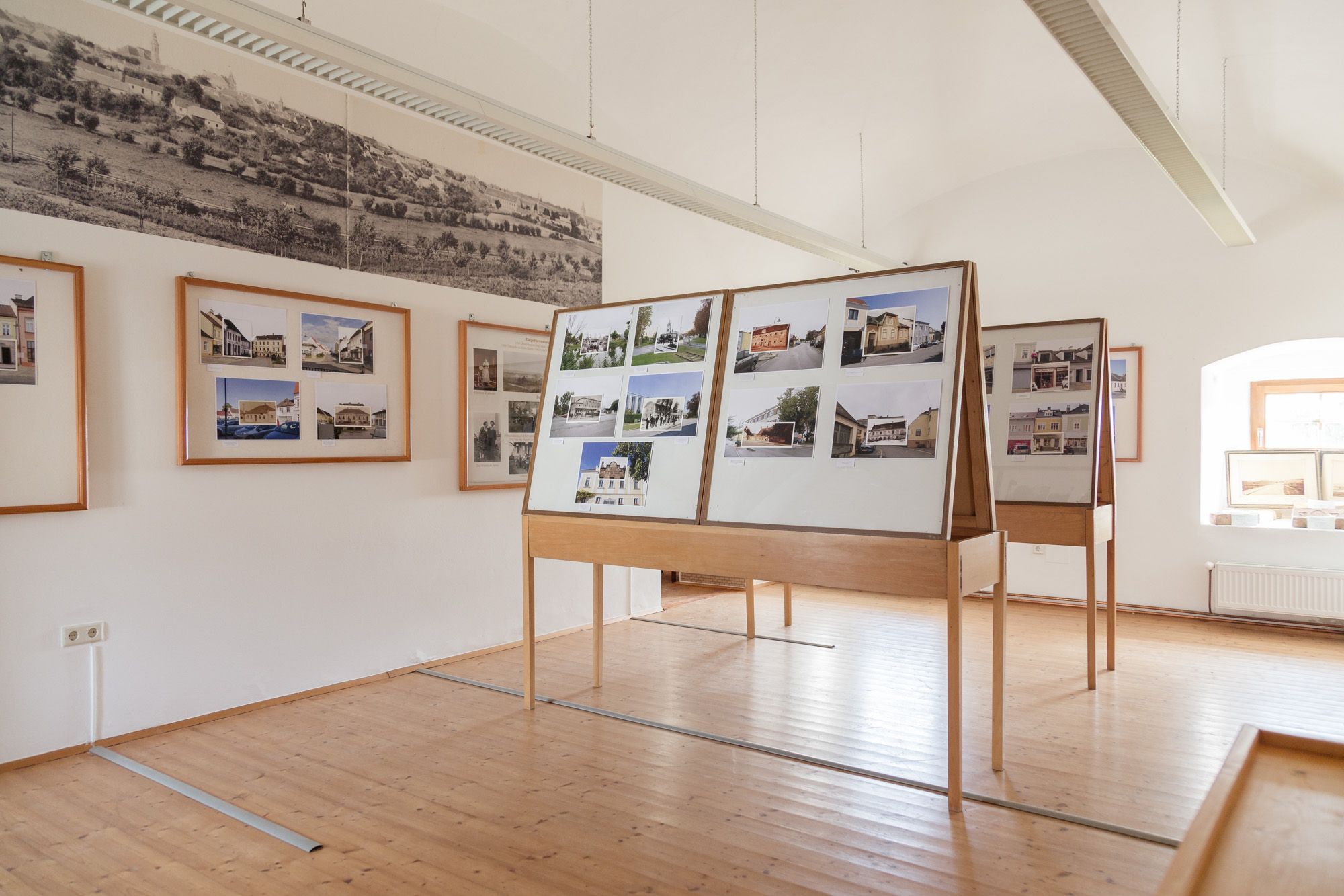 Belső nézet egy múzeumi helyiségből, a falakon fotópanelekkel és történelmi képekkel.