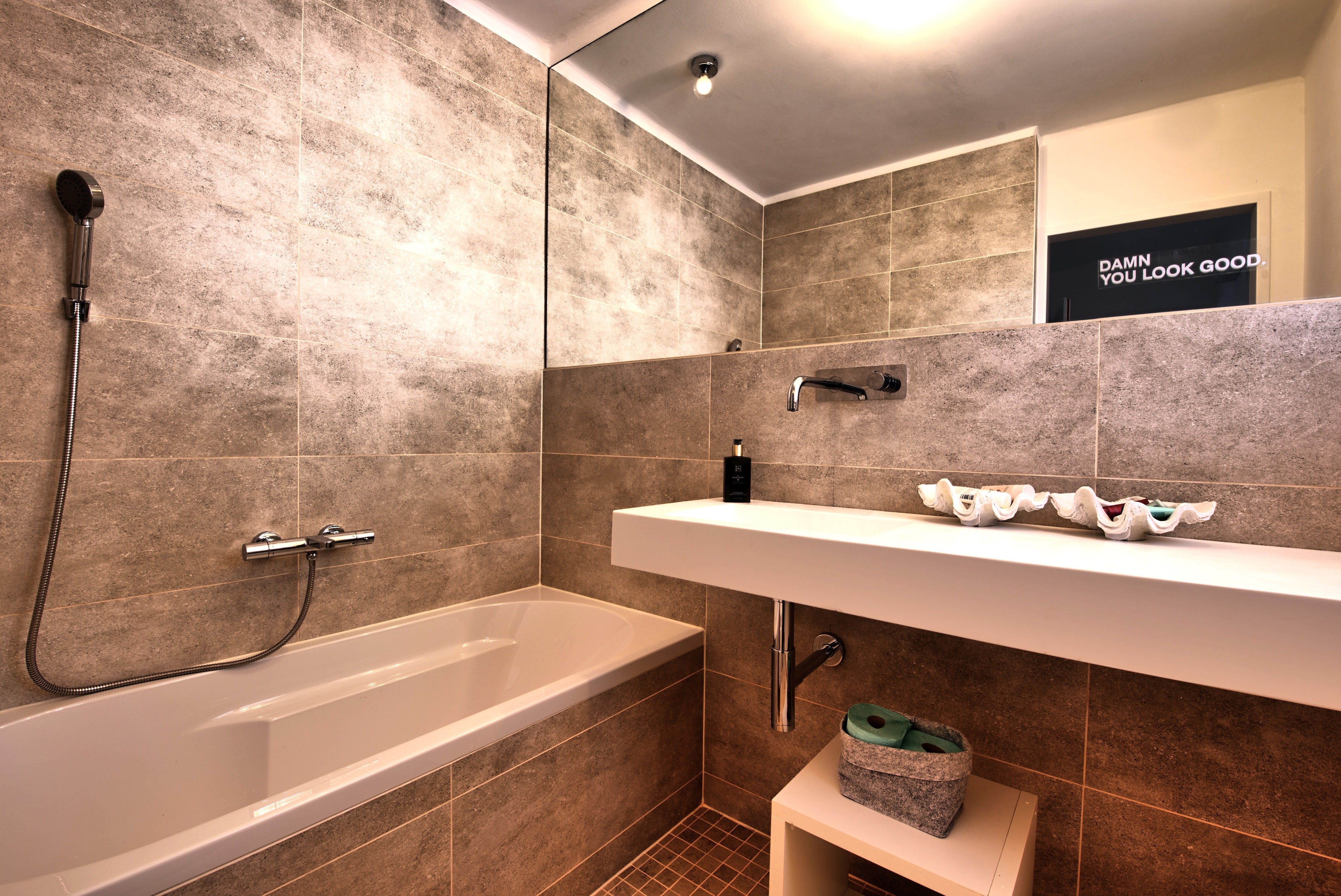 Modern fürdőszoba káddal, mosdókagylóval és nagy tükörrel.