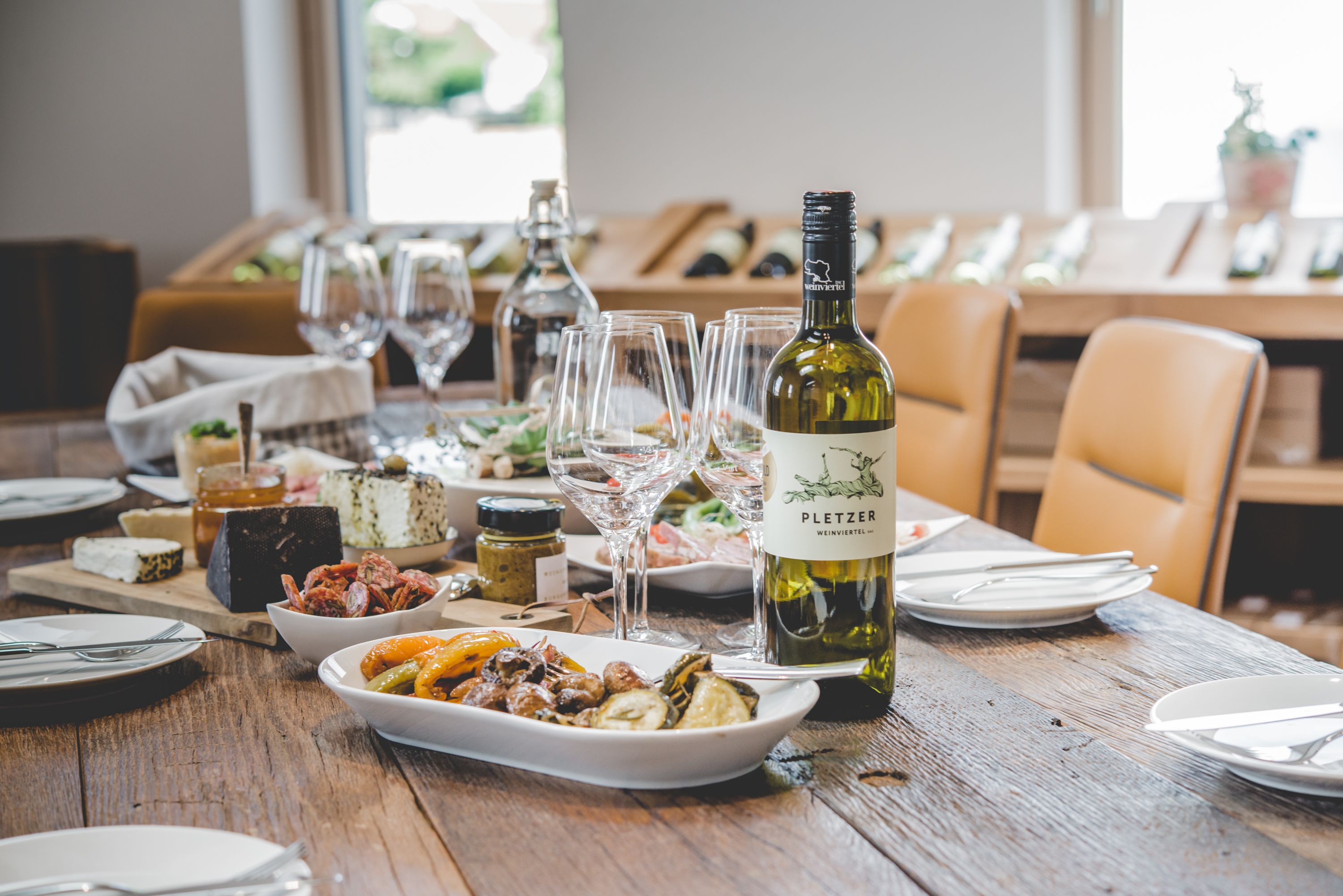 Egy megterített asztal egy üveg borral, poharakkal és különböző edényekkel.