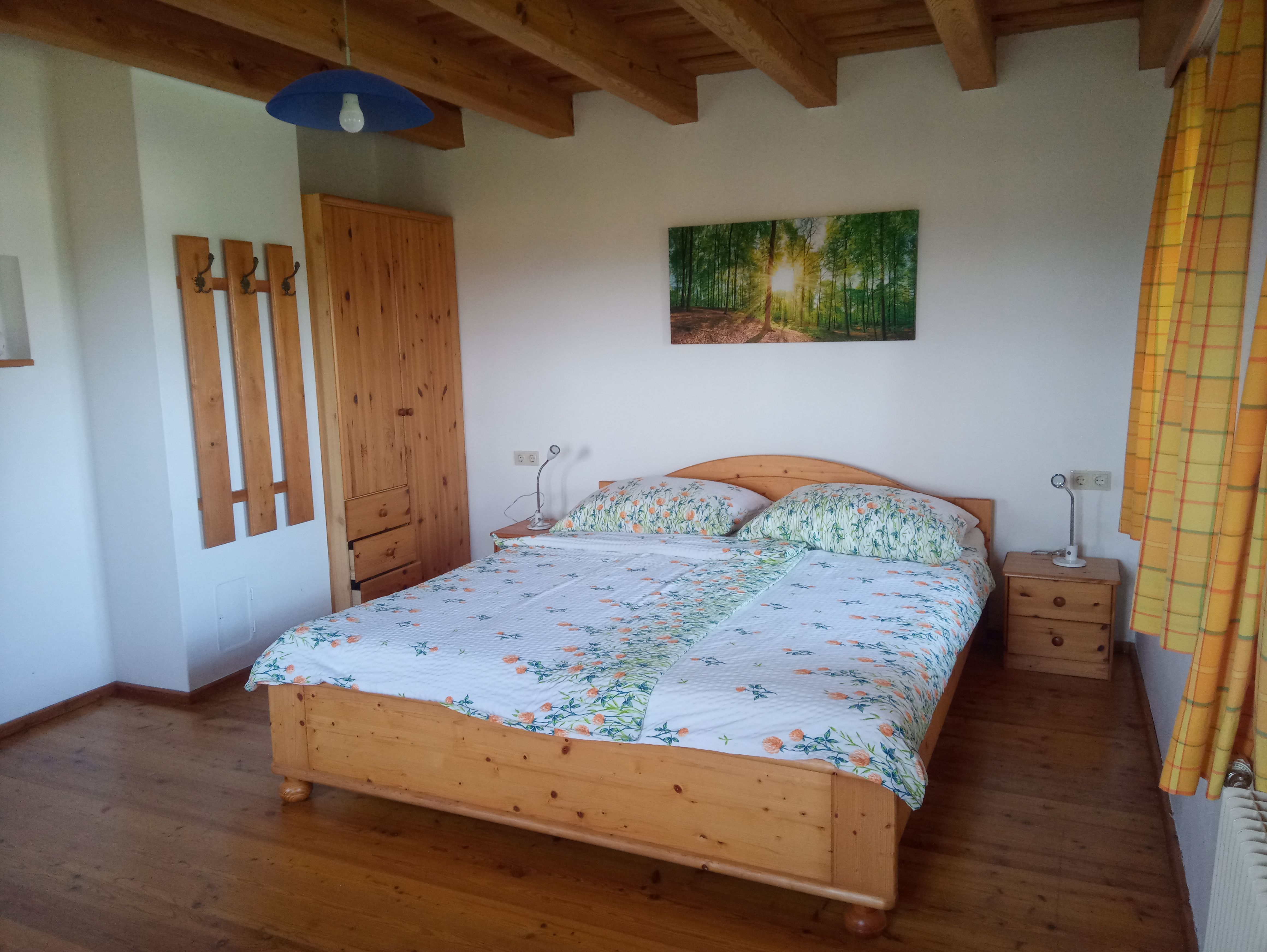 Hálószoba faággyal, éjjeliszekrénnyel, szekrénnyel és erdei falfestménnyel.