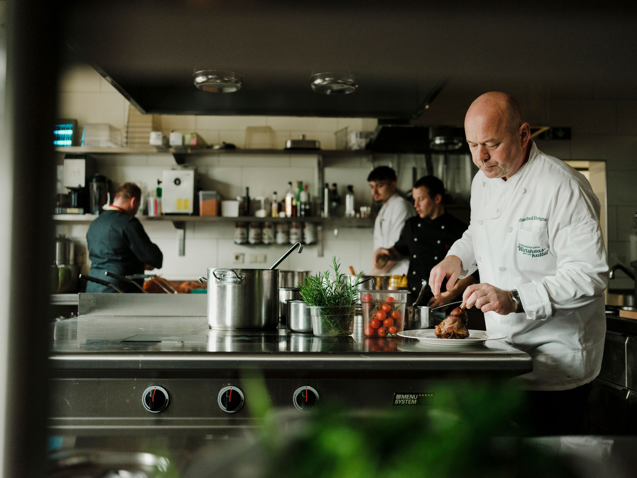A szakácsok egy profi konyhában dolgoznak, az egyikük húst vág.