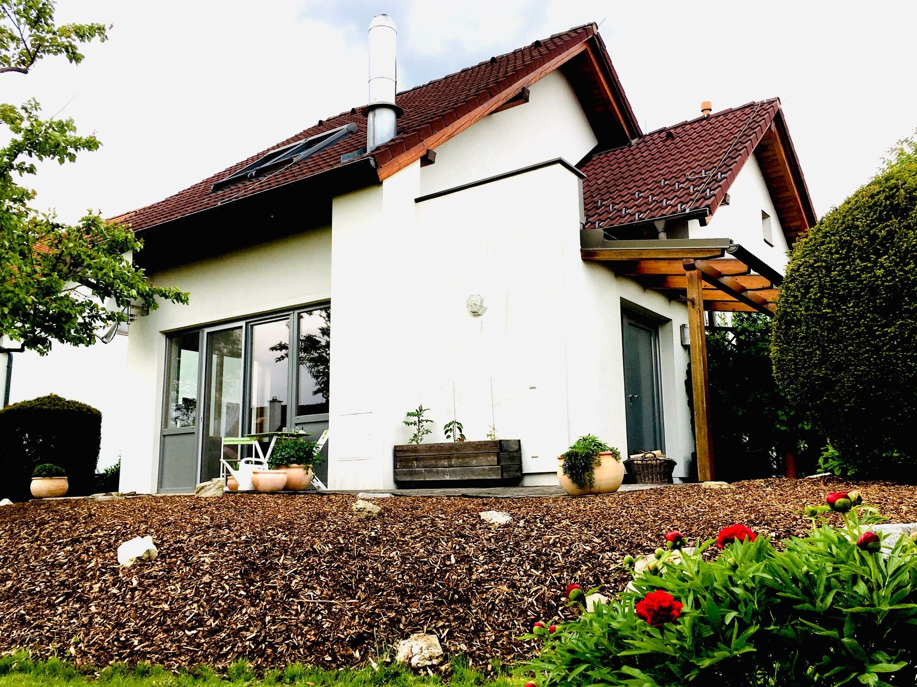 Egy modern családi ház külső nézete kerttel és terasszal.