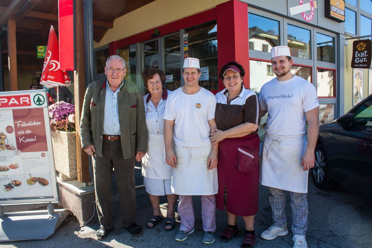 Öt ember áll mosolyogva egy üzlet bejárata előtt.