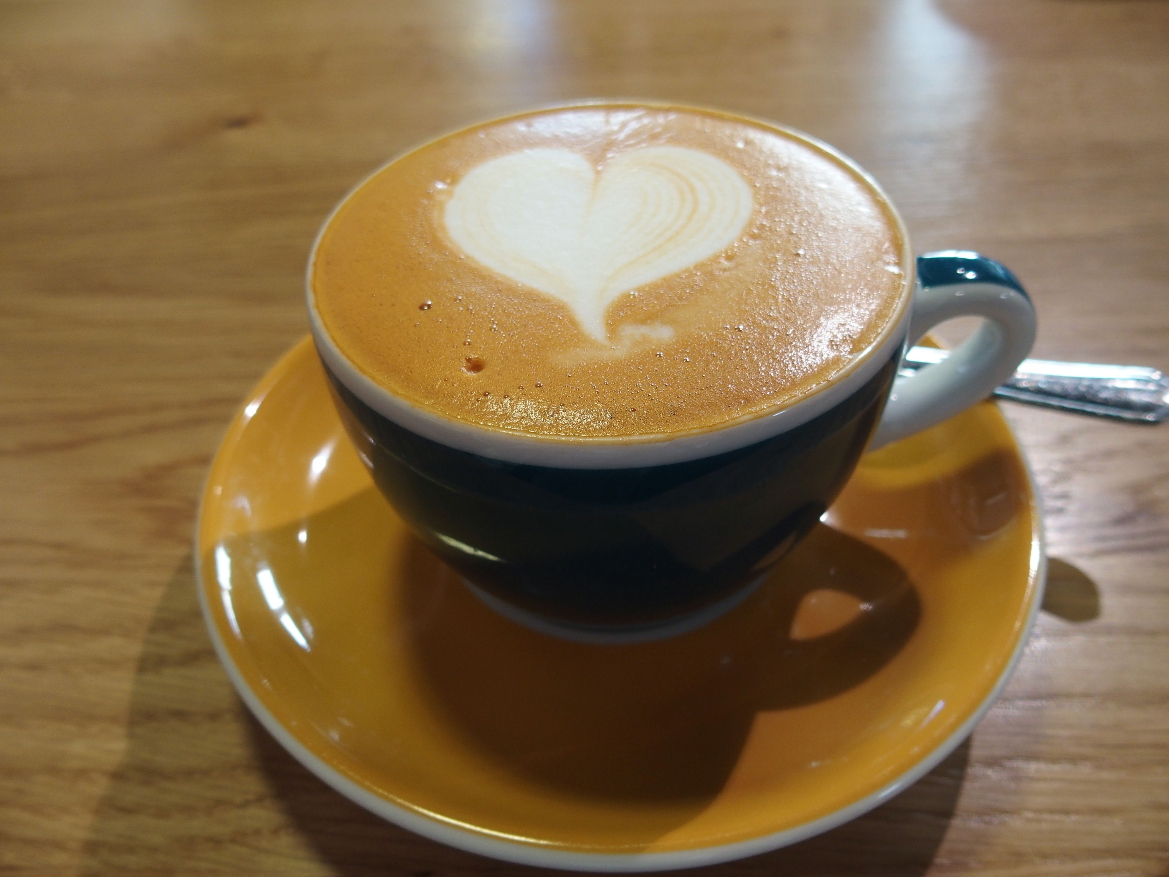 Egy csésze cappuccino egy szív alakú tejeskávéval egy faasztalon.