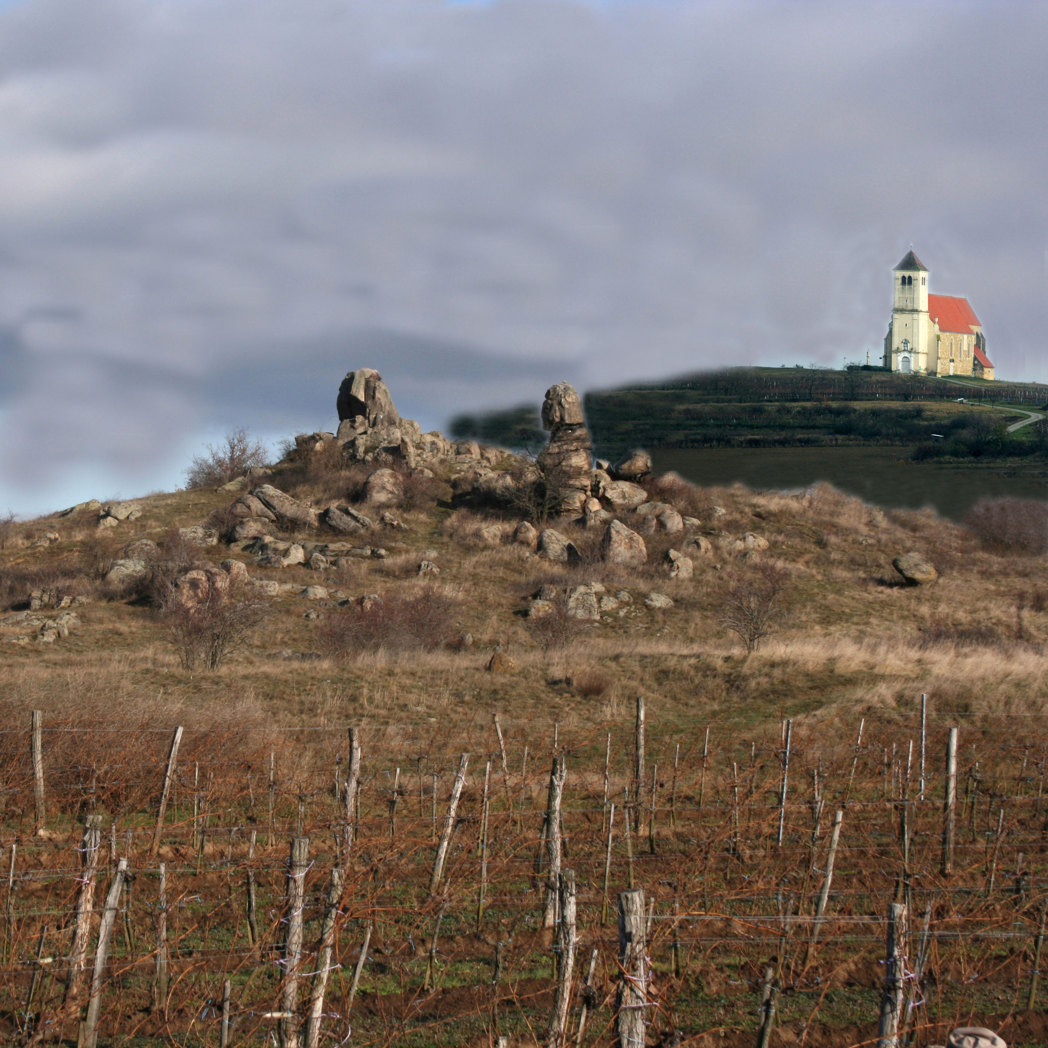 Tájkép sziklaalakzatokkal és templommal a háttérben.