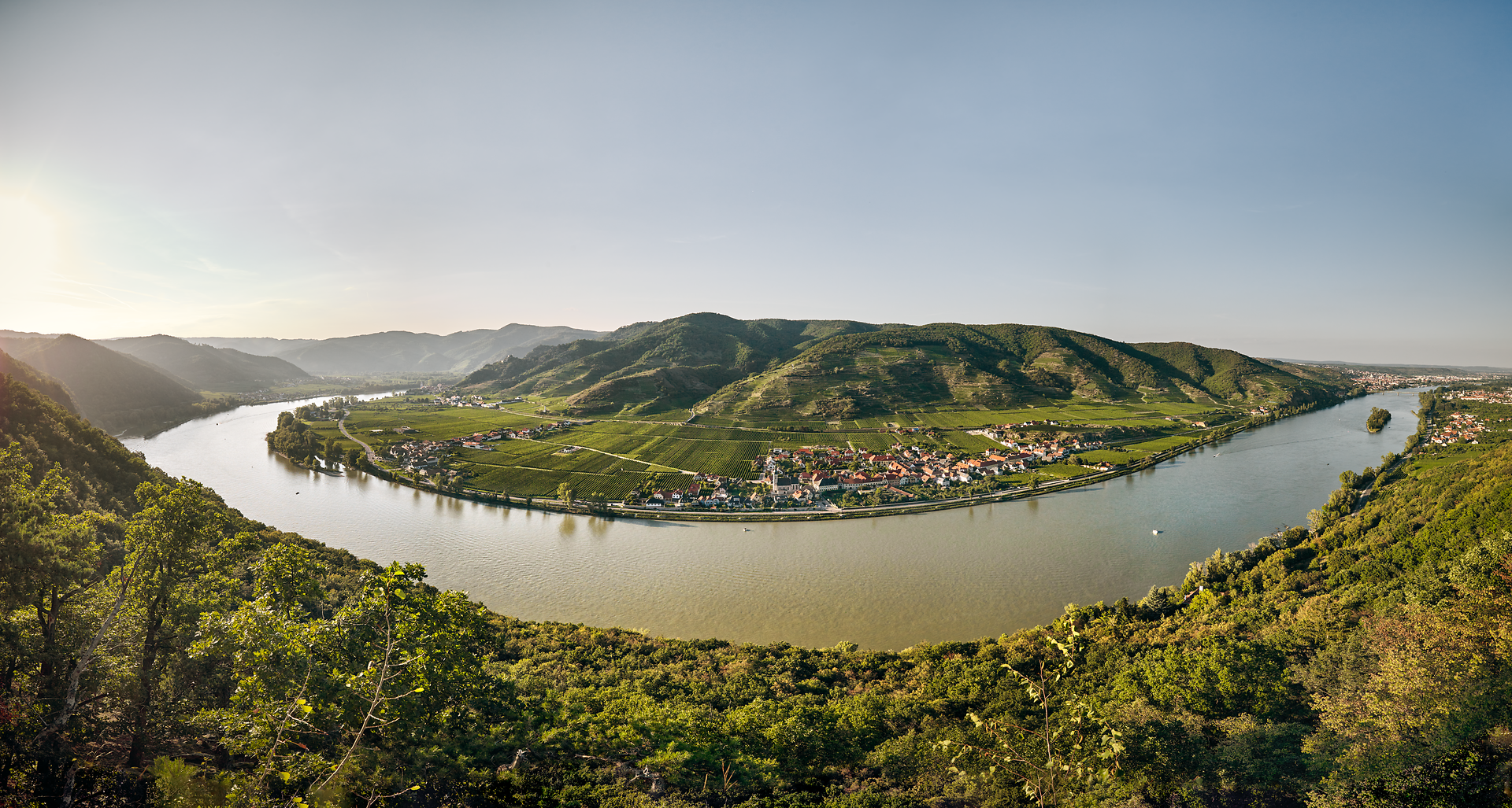 Die sanften Hügel des Dunkelsteinerwaldes umarmen die Donau, während die goldenen Strahlen der Abendsonne die Landschaft in ein warmes Licht tauchen. Hier, wo die Natur in voller Pracht erblüht, laden die malerischen Weinberge und charmanten Dörfer zu unvergesslichen Erlebnissen ein.