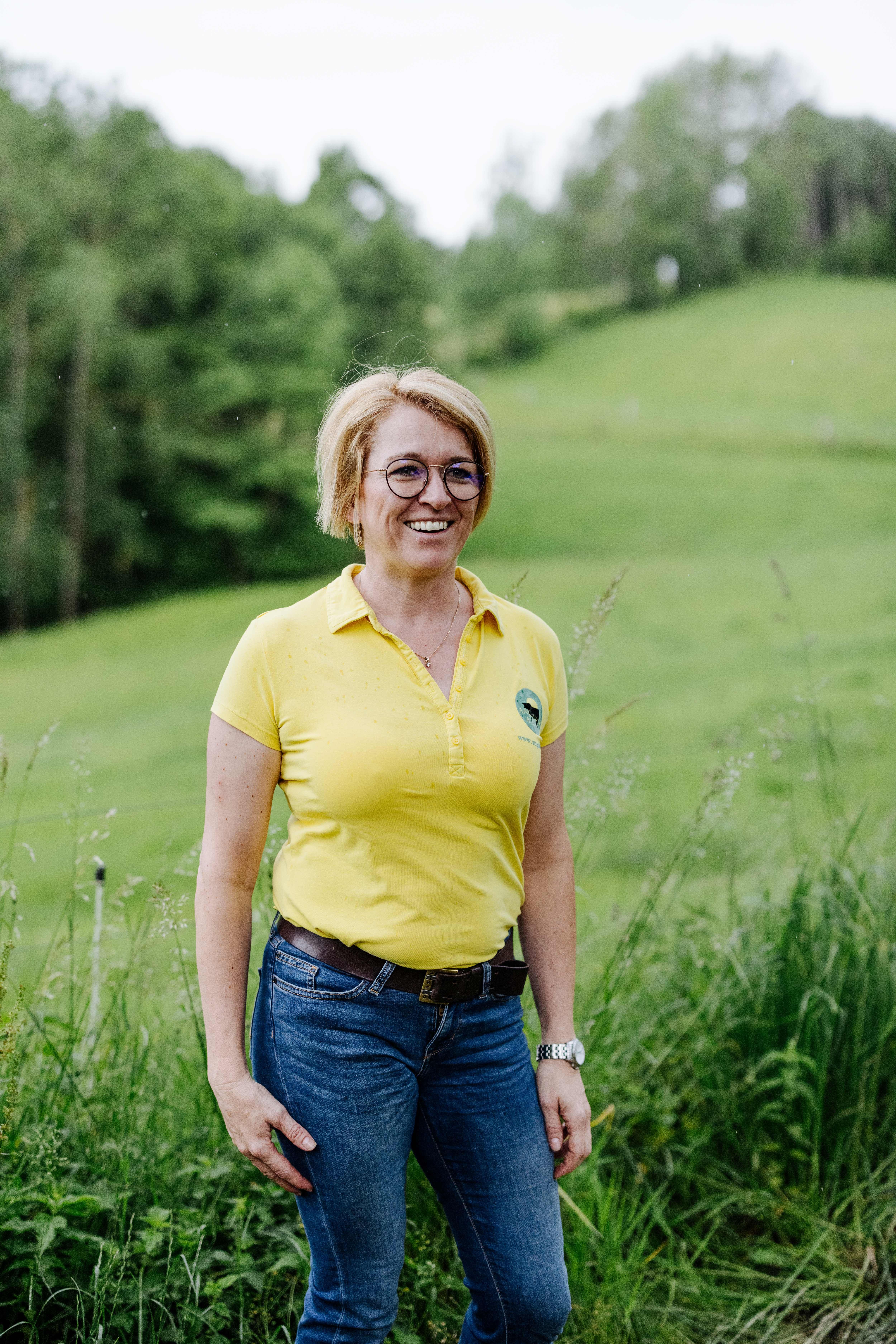 A tulajdonos, Sandra Anderl mosolyogva áll a zöld réten.