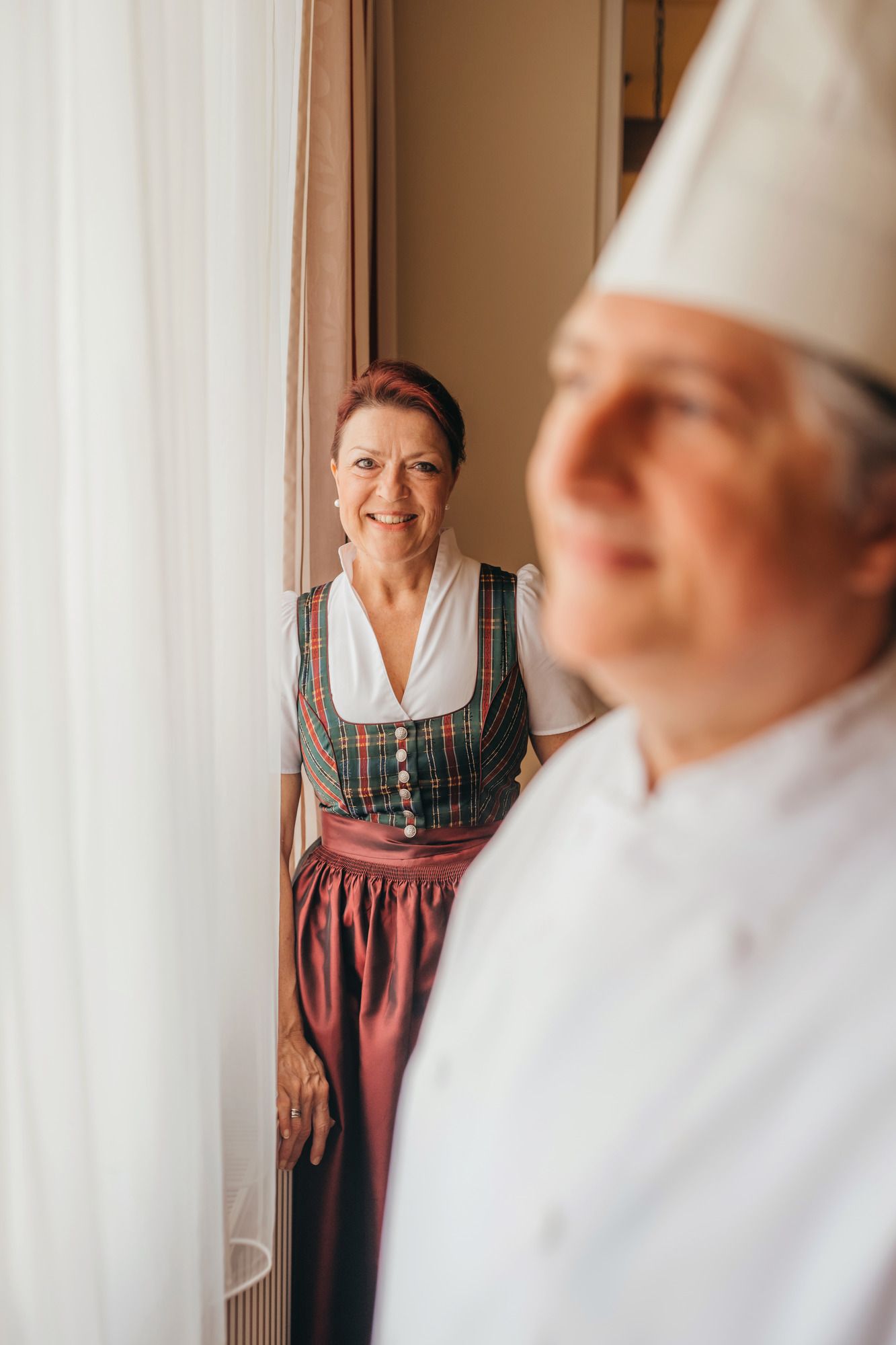 Egy hagyományos ruhás nő áll egy fehér egyenruhás szakácsnő mellett.