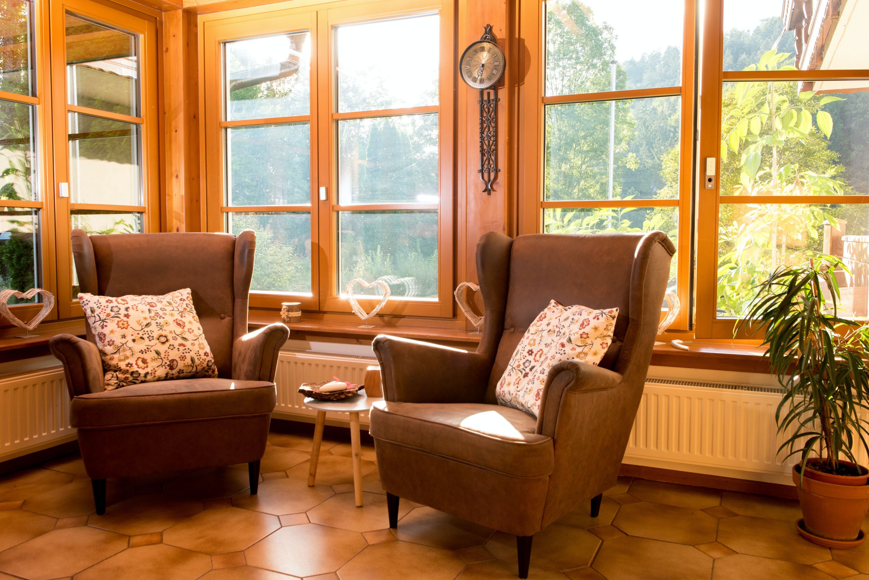 Két barna fotel mintás párnákkal a nagy ablakok előtt egy napos szobában.