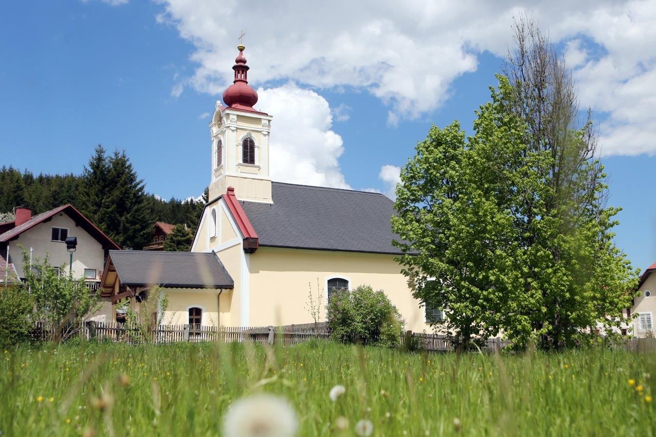 Mitterbachi templom piros toronnyal és zöld fával az előtérben.
