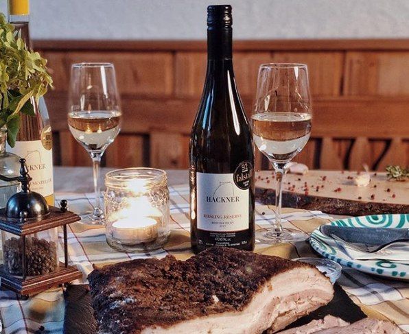 Asztal borosüveggel, két pohárral, gyertyával és hústállal.