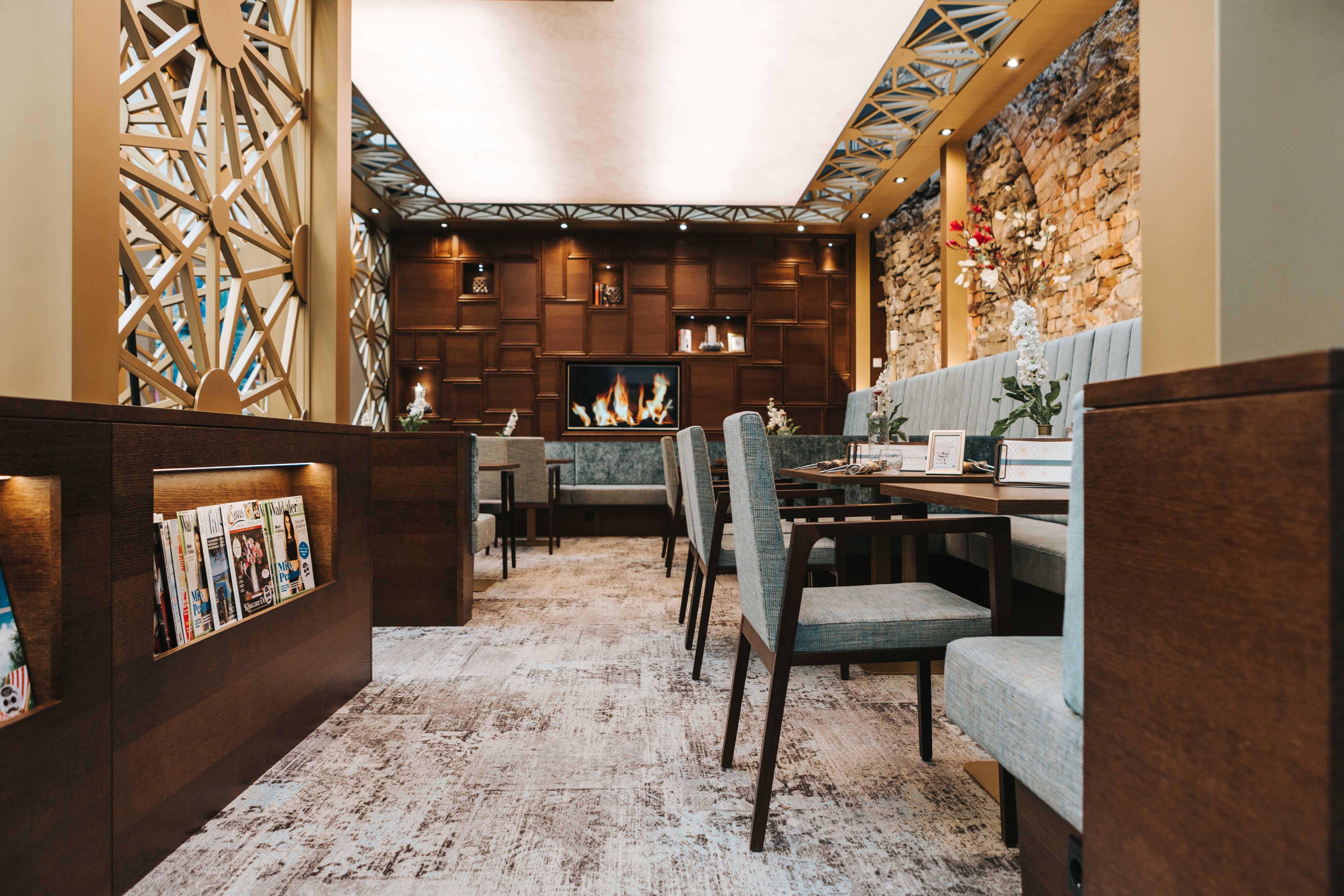 Egy stílusos kávézó belső nézete hangulatos ülőhelyekkel, kandallóval és magazinállvánnyal.