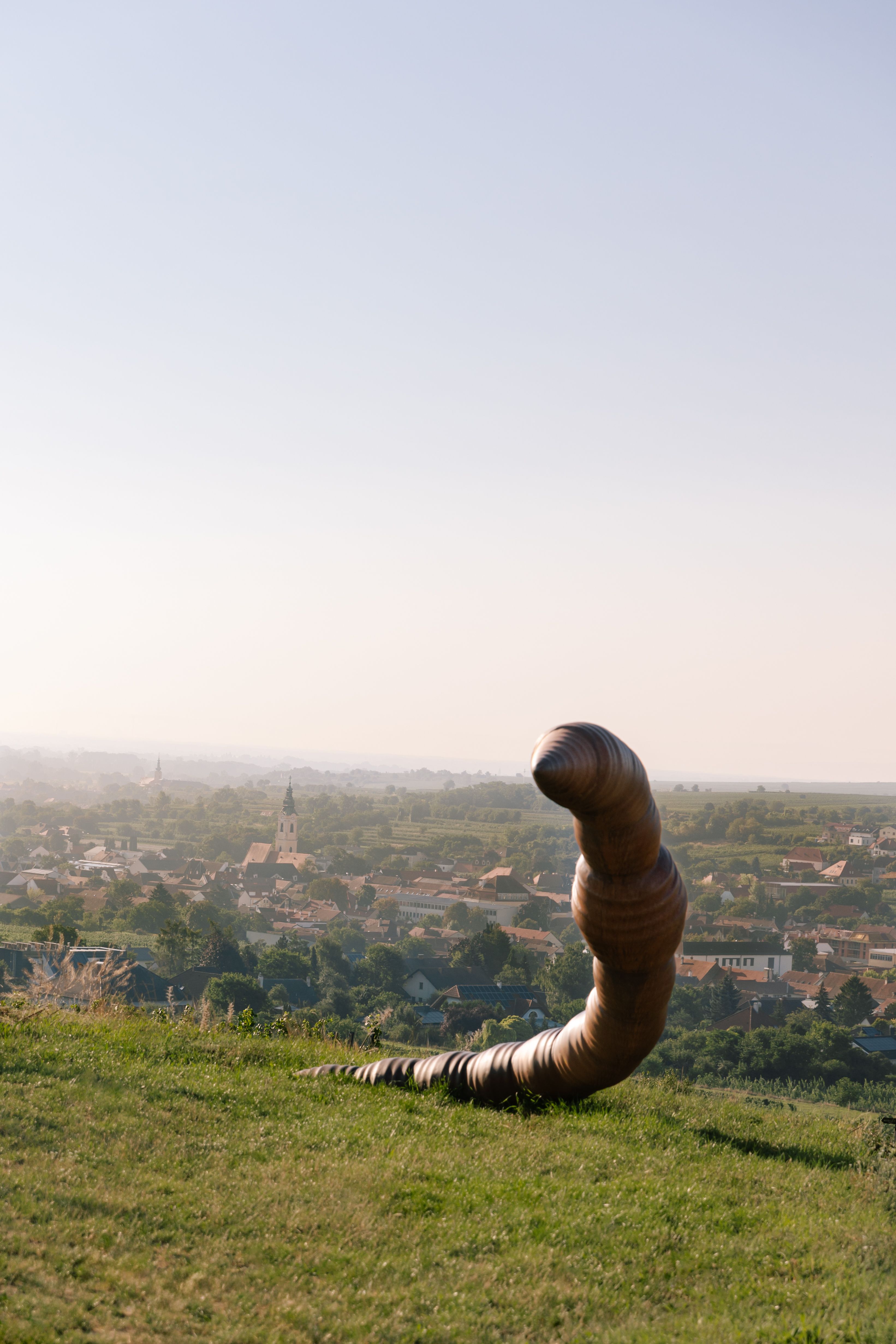 Ein kunstvolles Werk erhebt sich majestätisch über die sanften Hügel des Kamptals und bietet einen faszinierenden Kontrast zur idyllischen Landschaft. Die warmen Sonnenstrahlen des Sommers lassen die Umgebung erstrahlen und laden dazu ein, die Schönheit der Natur und die Kunst im öffentlichen Raum zu genießen.