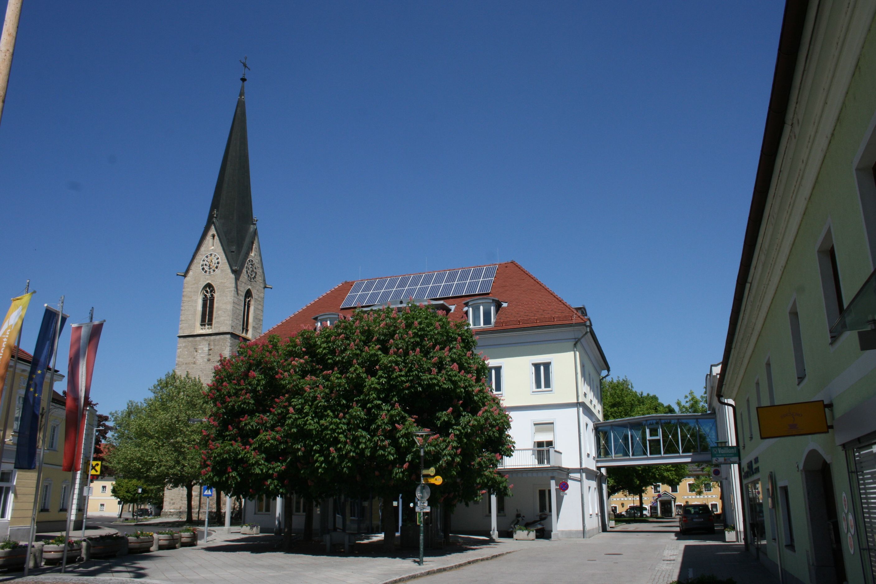 Templomtorony és épület Szent Valentinban kék égbolt mellett.