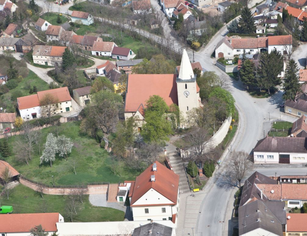 Légi felvétel egy templomról egy faluban, a környező házakkal és utcákkal.