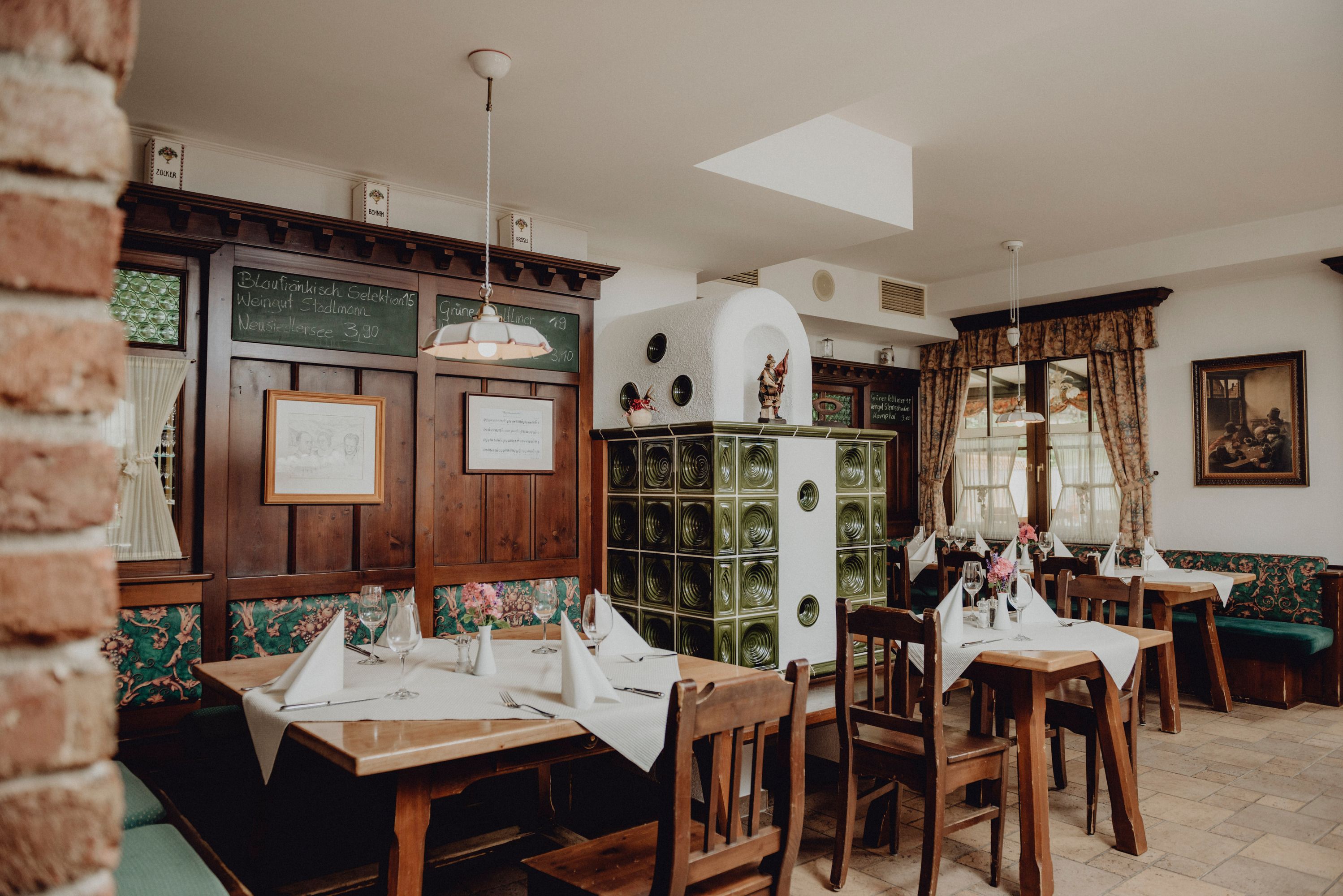 Hangulatos étterem fabútorokkal, cserépkályhával és díszített asztalokkal.