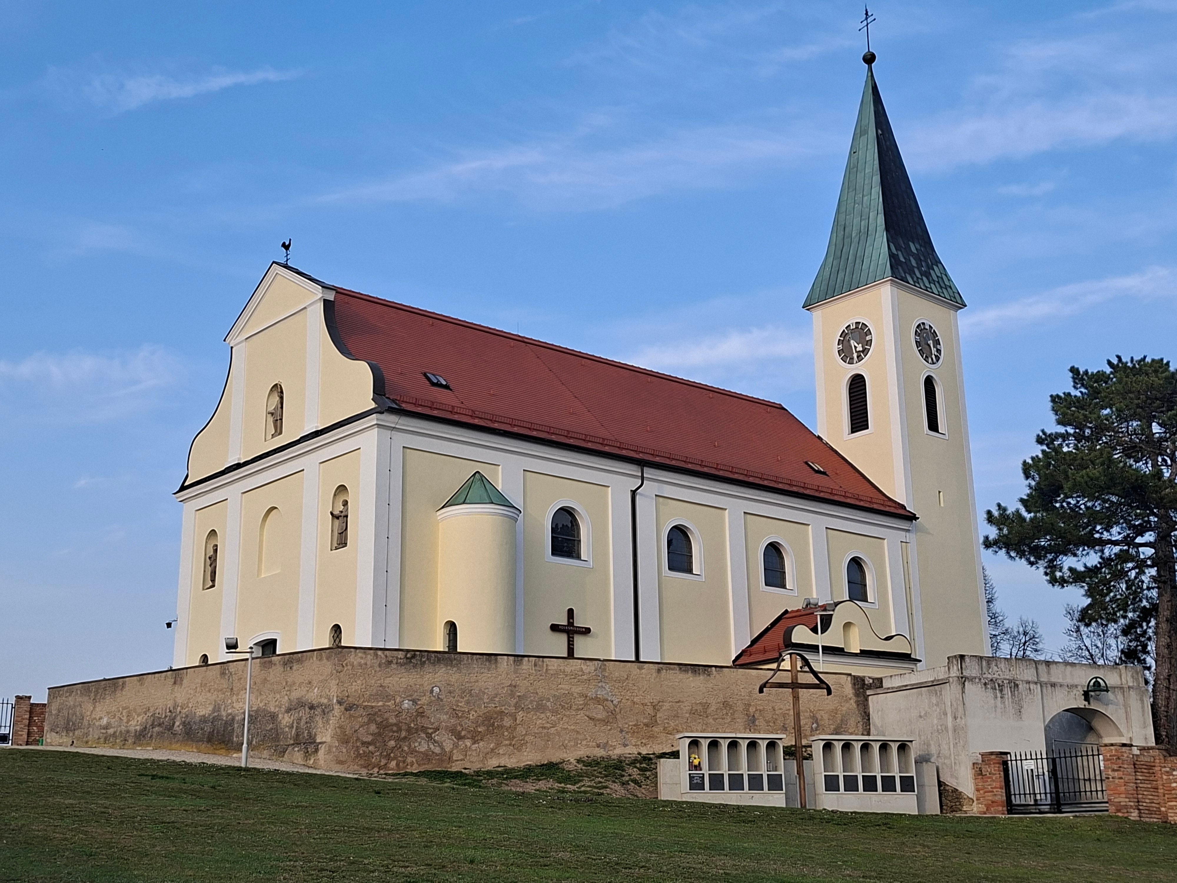 Templom sárga homlokzattal és piros tetővel a kék égbolt előtt.