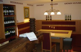 Egy bor&aacute;szat belső n&eacute;zete asztallal, sz&eacute;kekkel &eacute;s bortart&oacute;kkal.