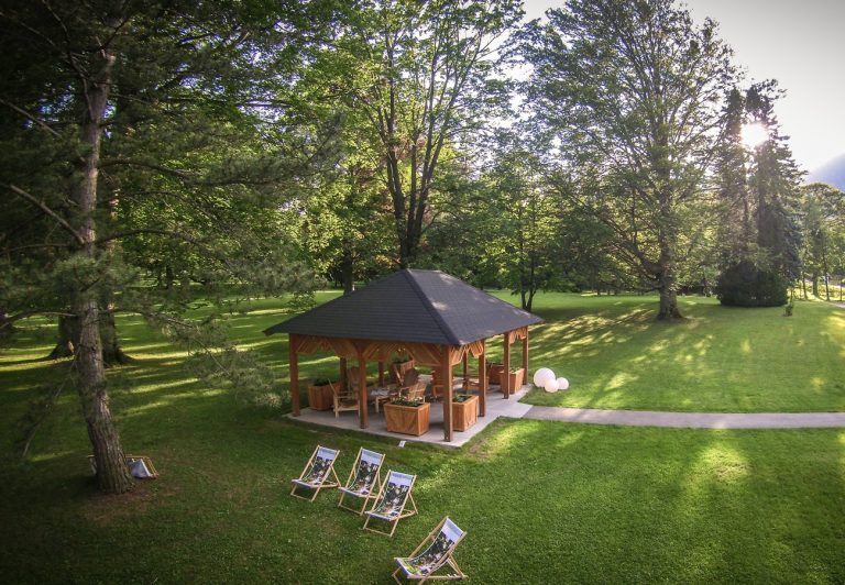 Egy pavilon a parkban, nyugágyakkal és fákkal.