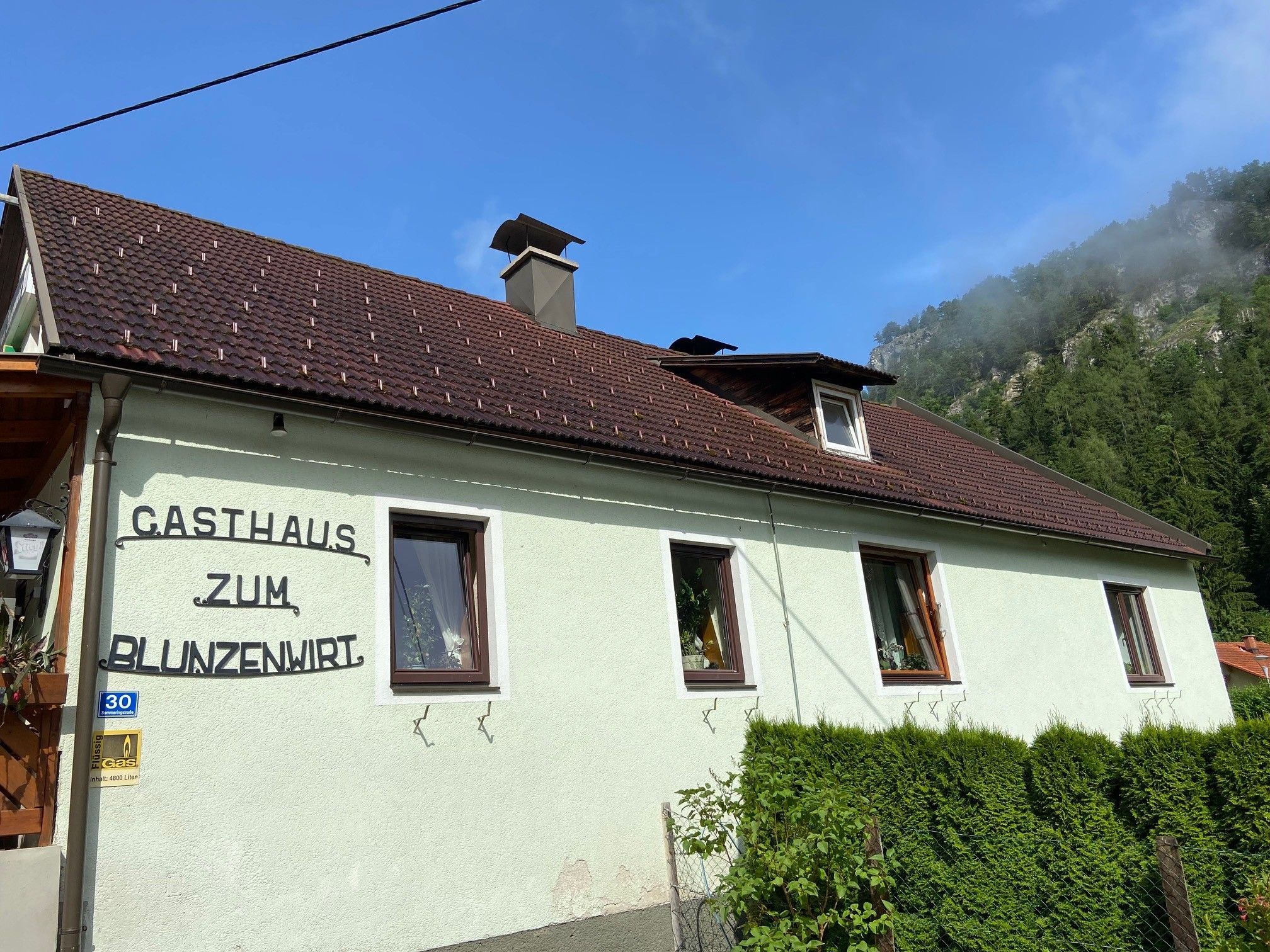 A Zum Blunzenwirt vendéglő külső nézete zöld festéssel és barna tetővel.