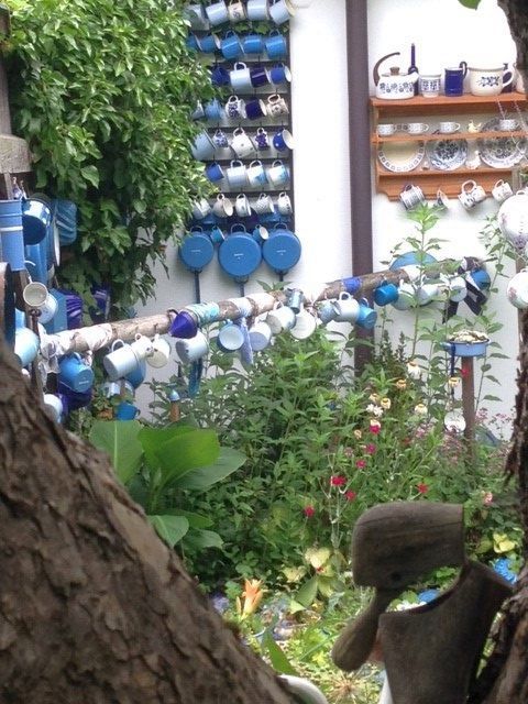 Egy kert sok színes csészével, amelyek a falakon és oszlopokon lógnak.