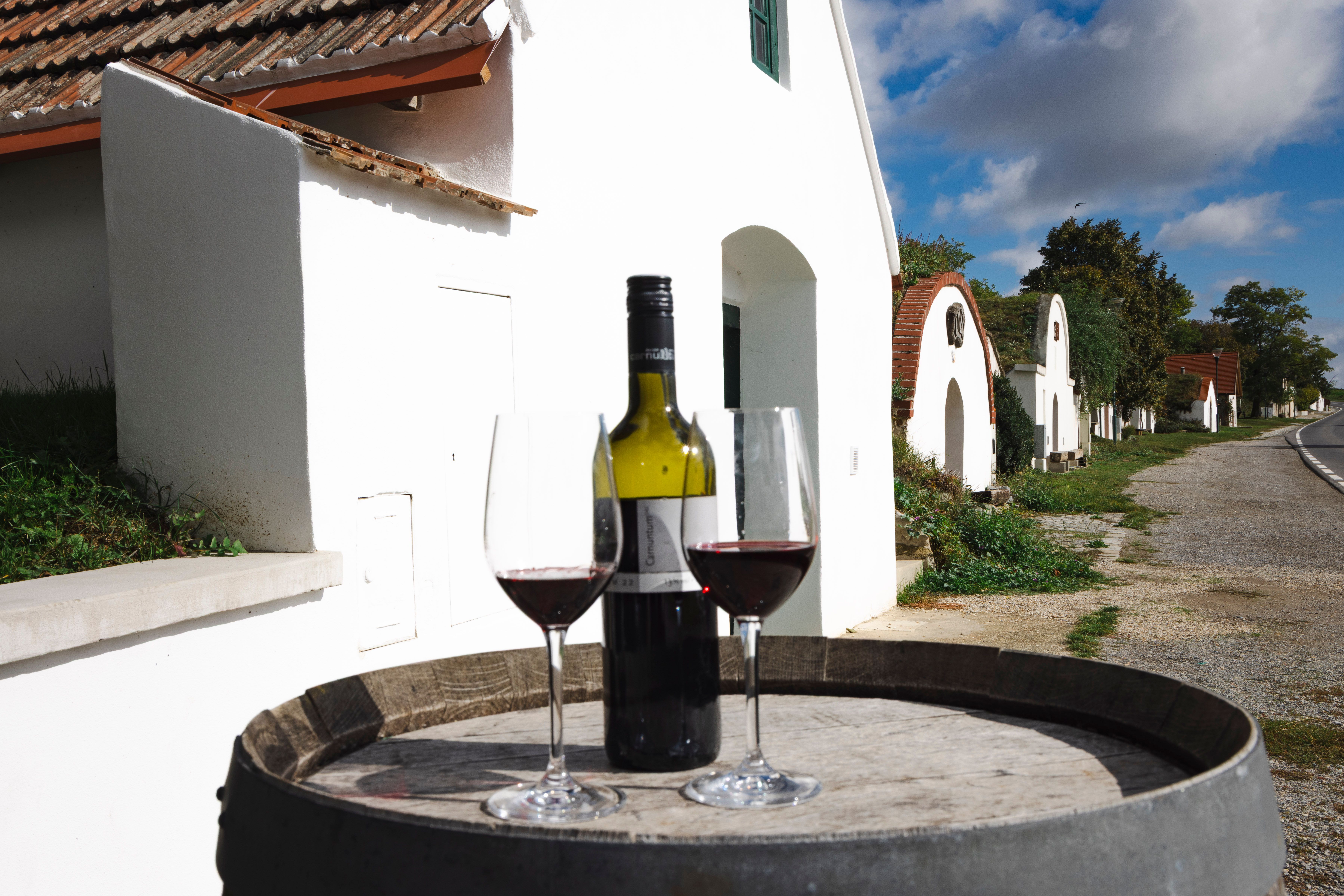 két borospohár és egy üveg vörösbor egy boroshordón, a háttérben a Pincesoron