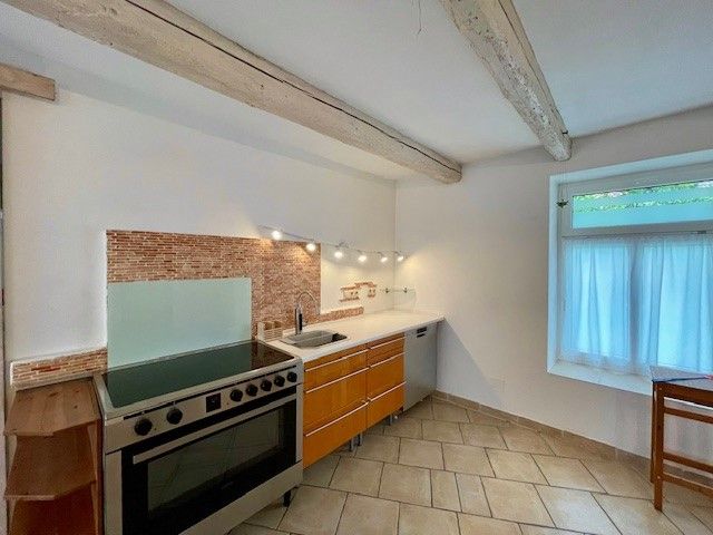 Modern konyha, tűzhely, fa szekrények és csempézett padló.