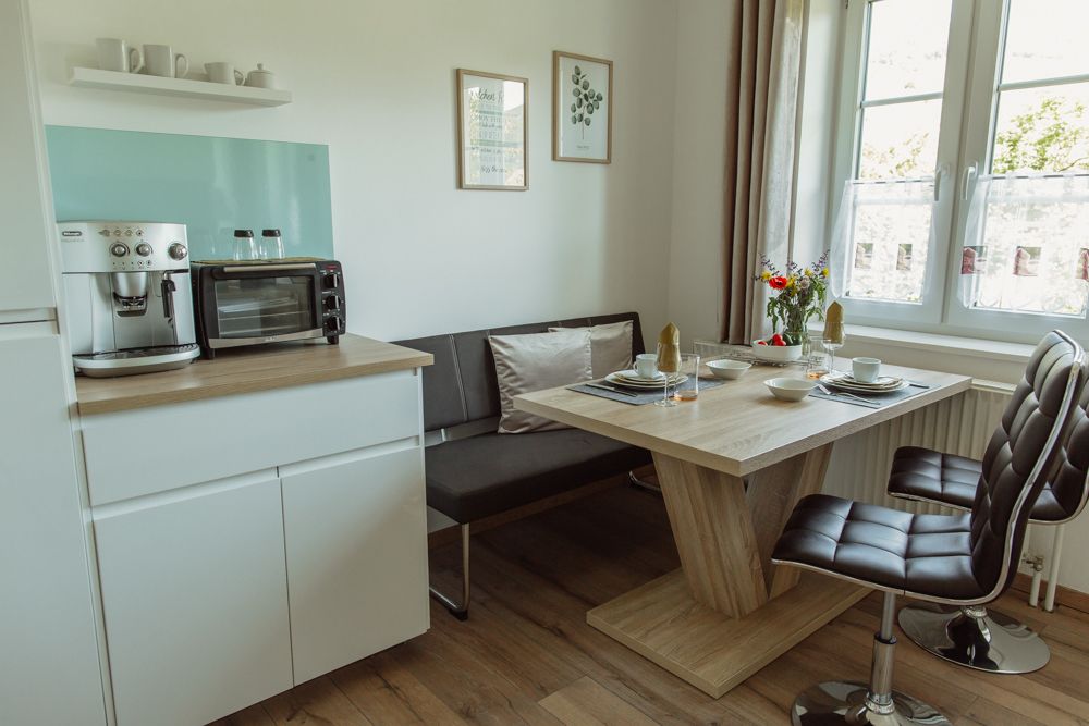 Modern konyha étkezőasztallal, székekkel és kávéfőzővel.