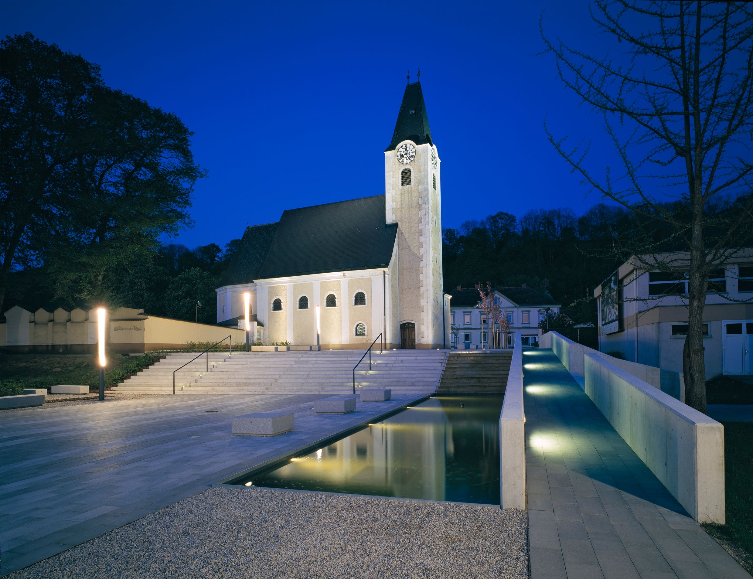 Esti felvétel egy kivilágított templomtérről, lépcsőkkel és vízmedencével Ernsthofenben.