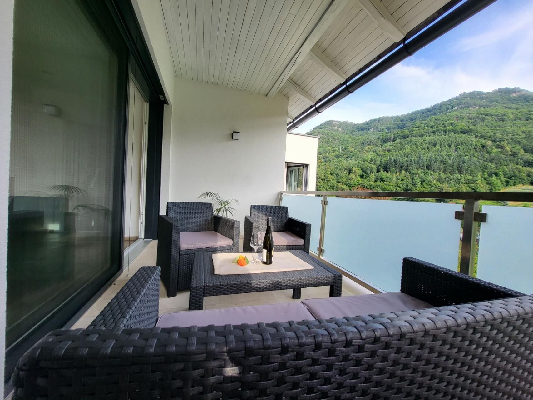 Erkély rattan bútorokkal és hegyre néző kilátással.