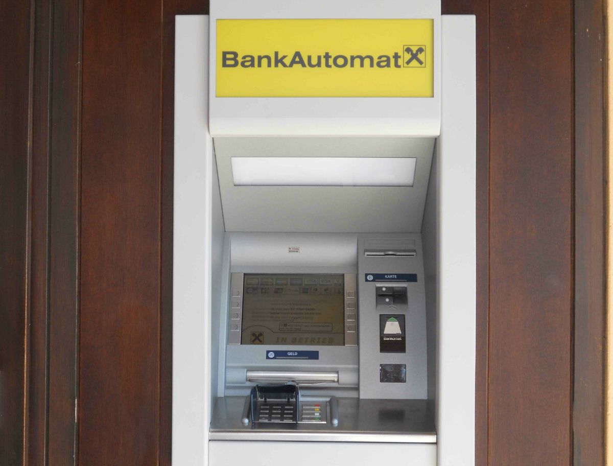 Egy bankautomata sárga felirattal és Raiffeisen logóval.