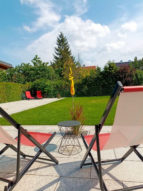 Két nyugágy a kertben, a háttérben pázsit és fák.