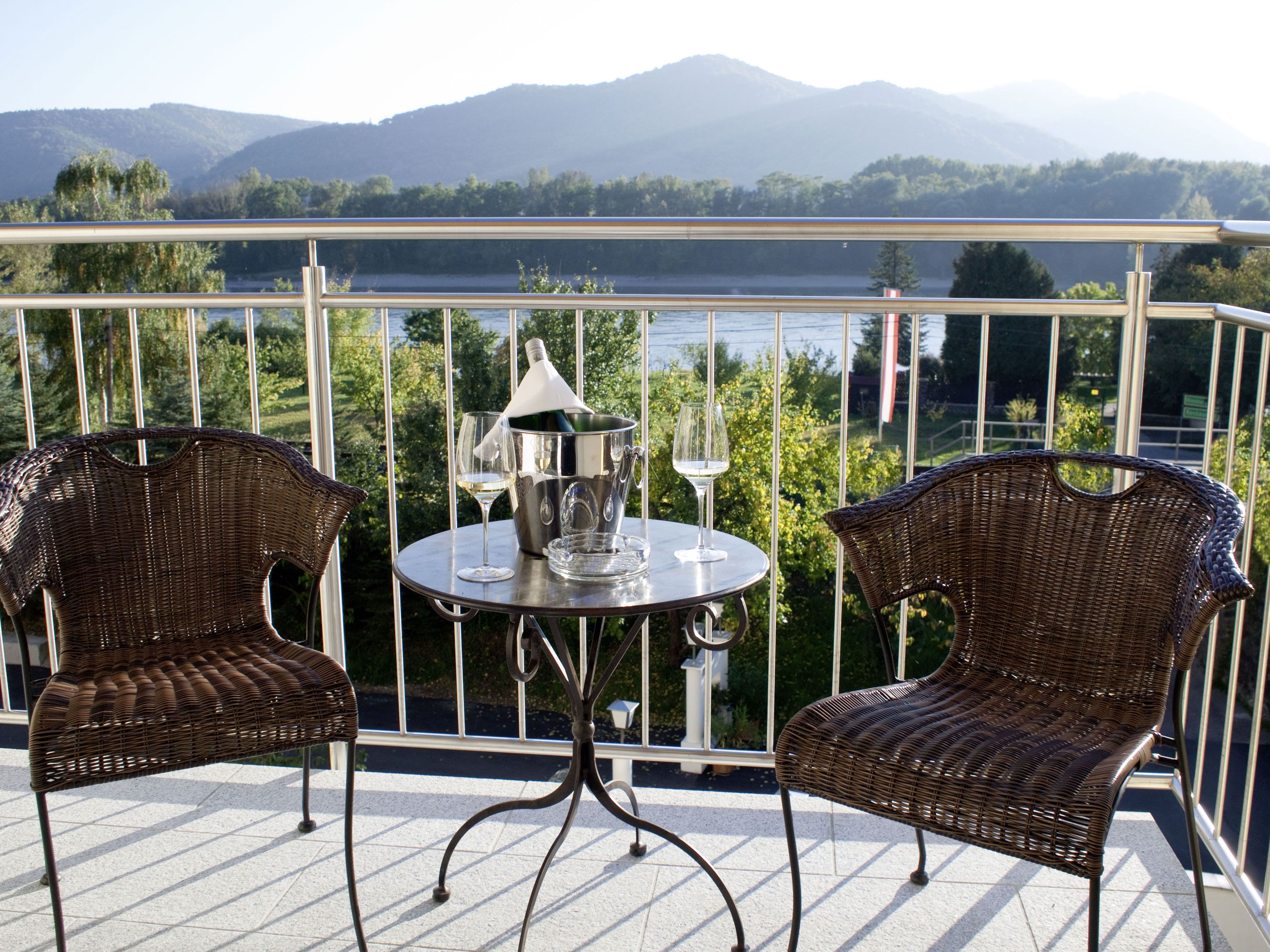 Két rattan szék és egy asztal pezsgőhűtővel a hegyre néző teraszon.