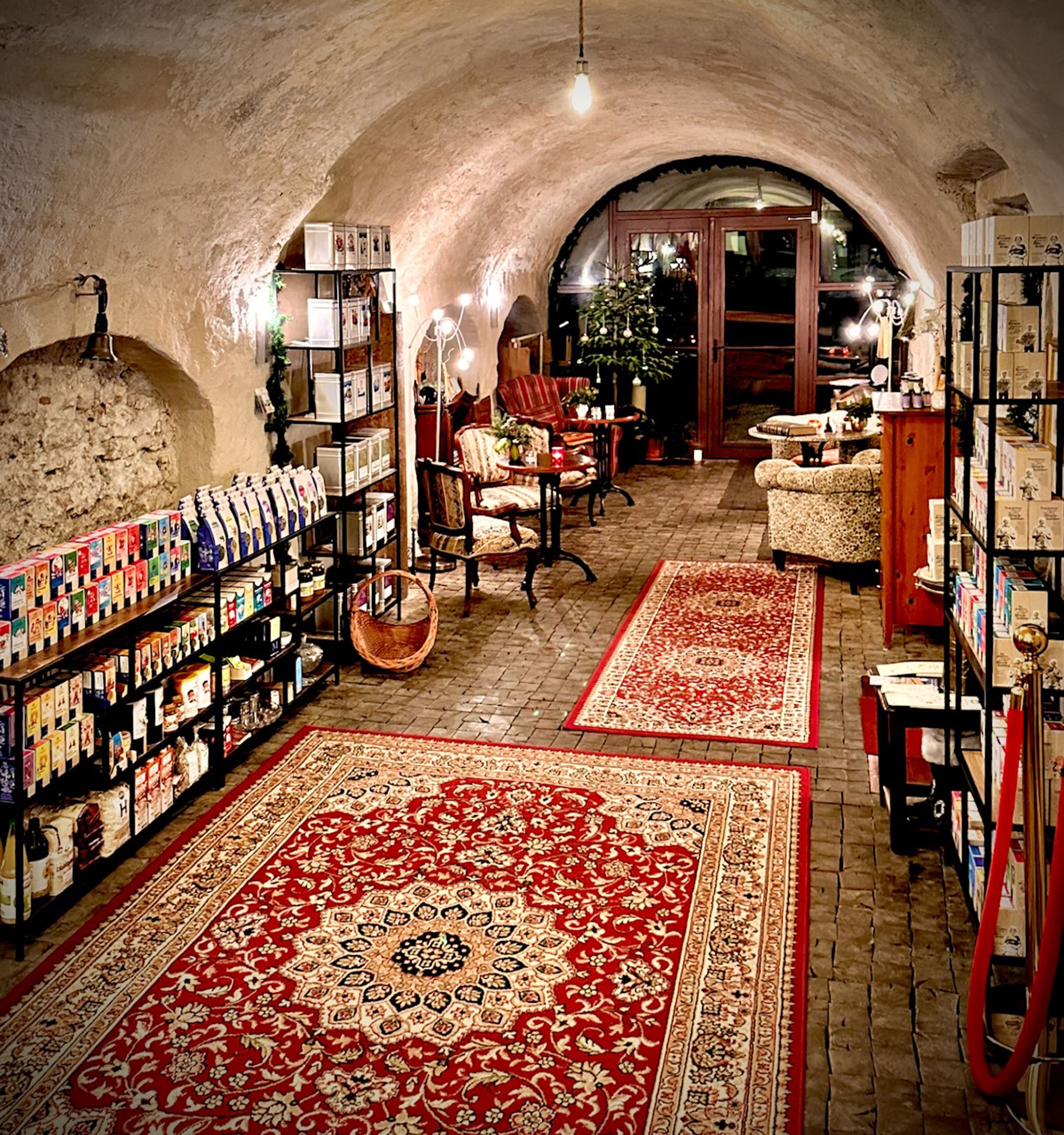 Hangulatos helyiség vörös szőnyegekkel, termékekkel teli polcokkal és ülőhelyekkel a teázóban.