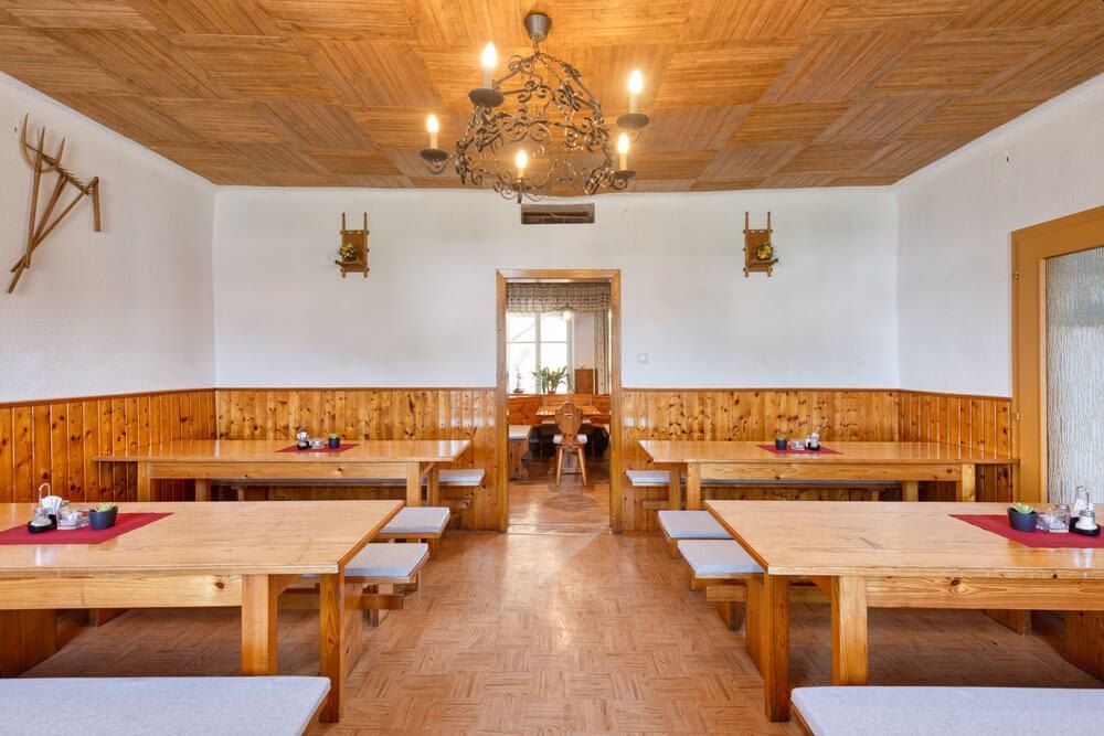 Egy hagyományos borozó belső nézete, fa asztalokkal és padokkal, fa falburkolattal és csillárral a mennyezeten.