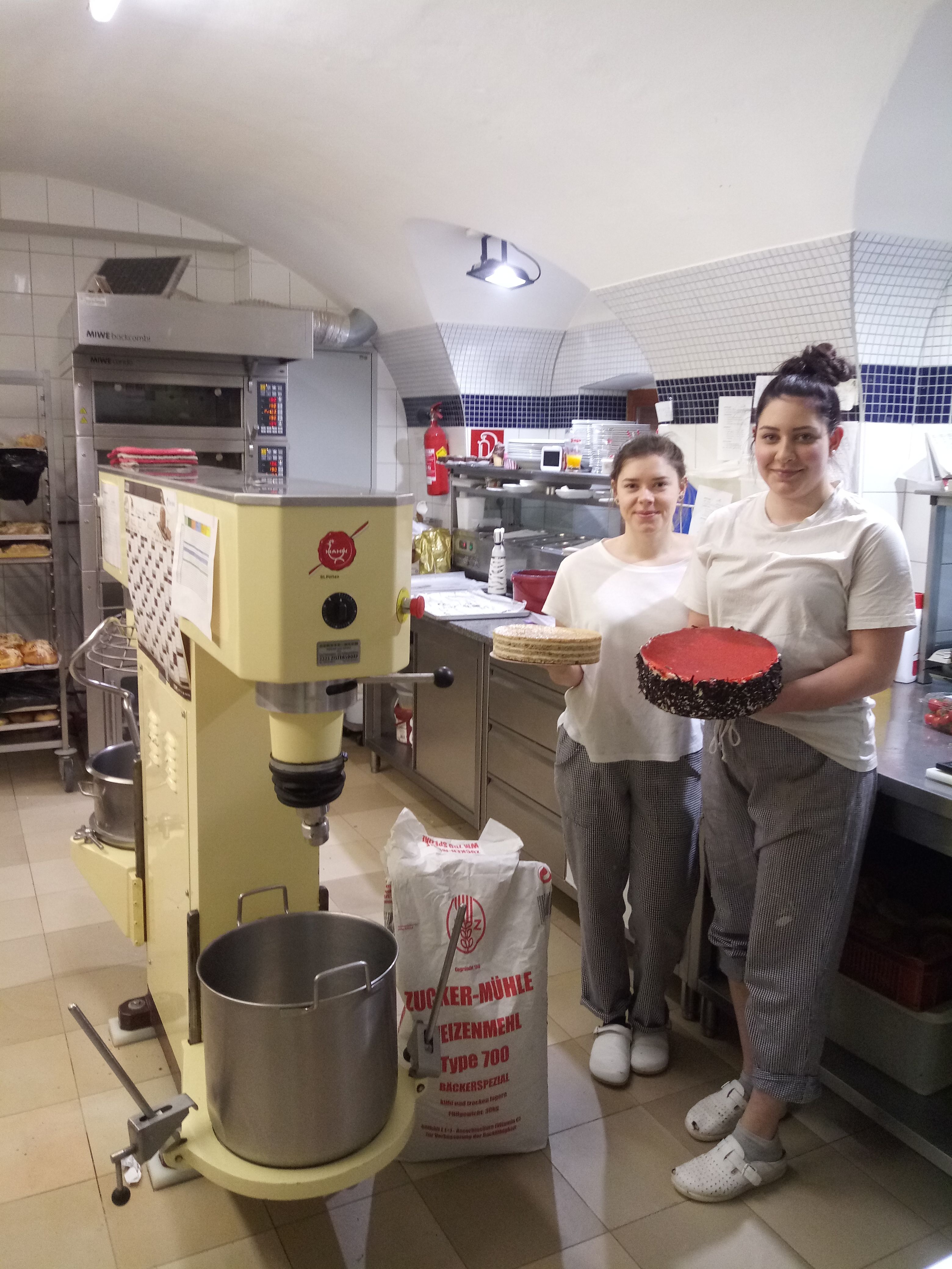 Két ember egy cukrászdában egy tortával és egy tortaalappal.