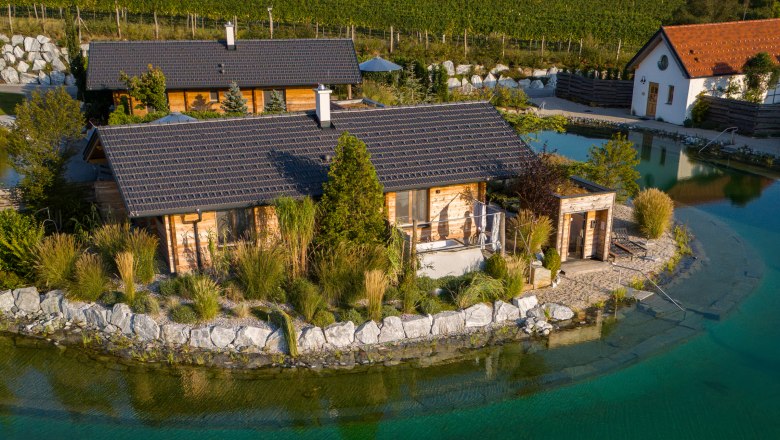 Kittenberger Chalets a Gartensee-nél, © Niederösterreich Werbung / Maximilian Pawlikowsky A kerti tavon lévő faházak légifelvétele stéggel és nyugágyakkal.