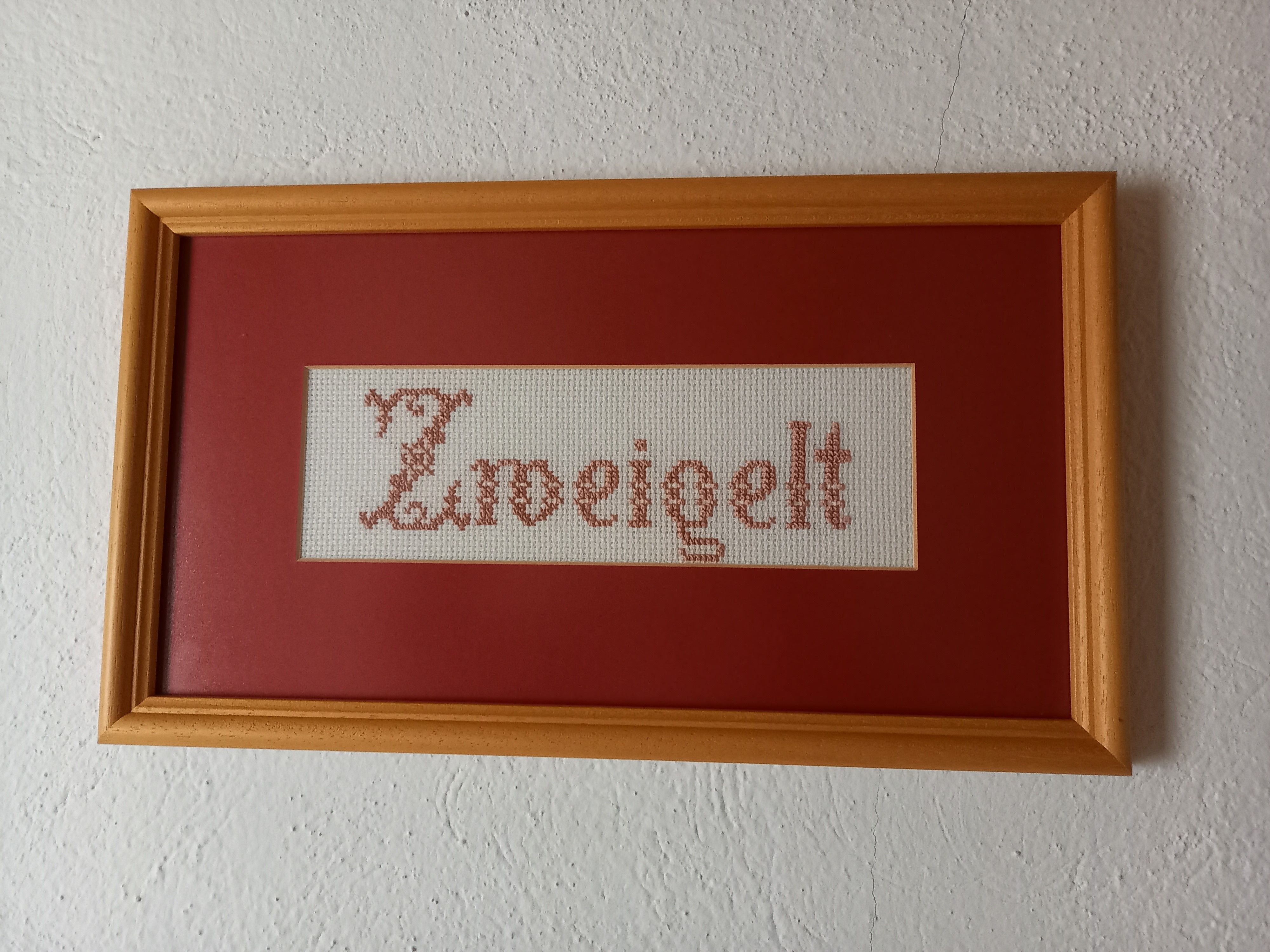 Hímzett kép a "Zweigelt" szóval, fakeretben.