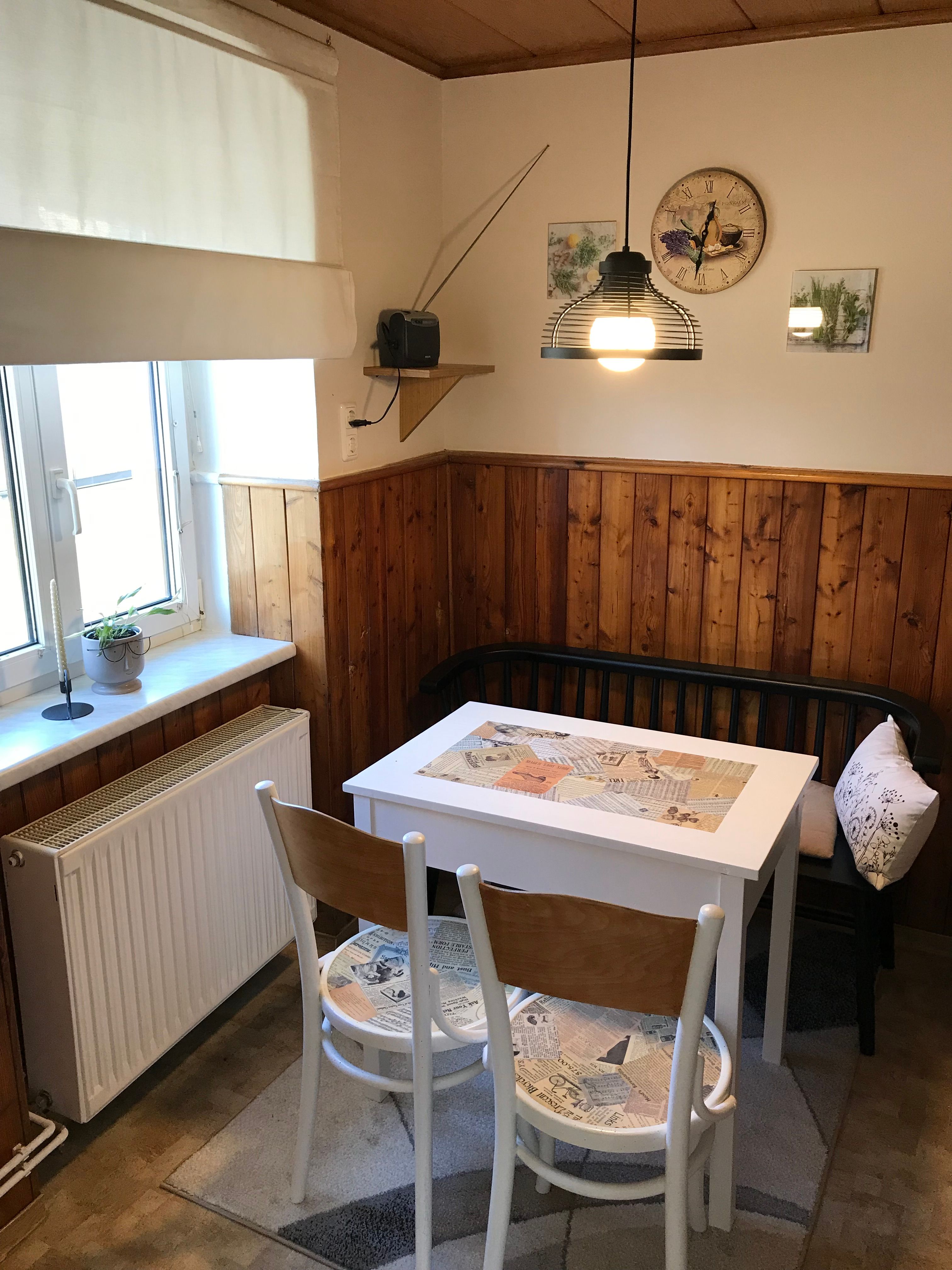 Kis étkező asztalokkal, székekkel és paddal a faburkolatú konyhában.