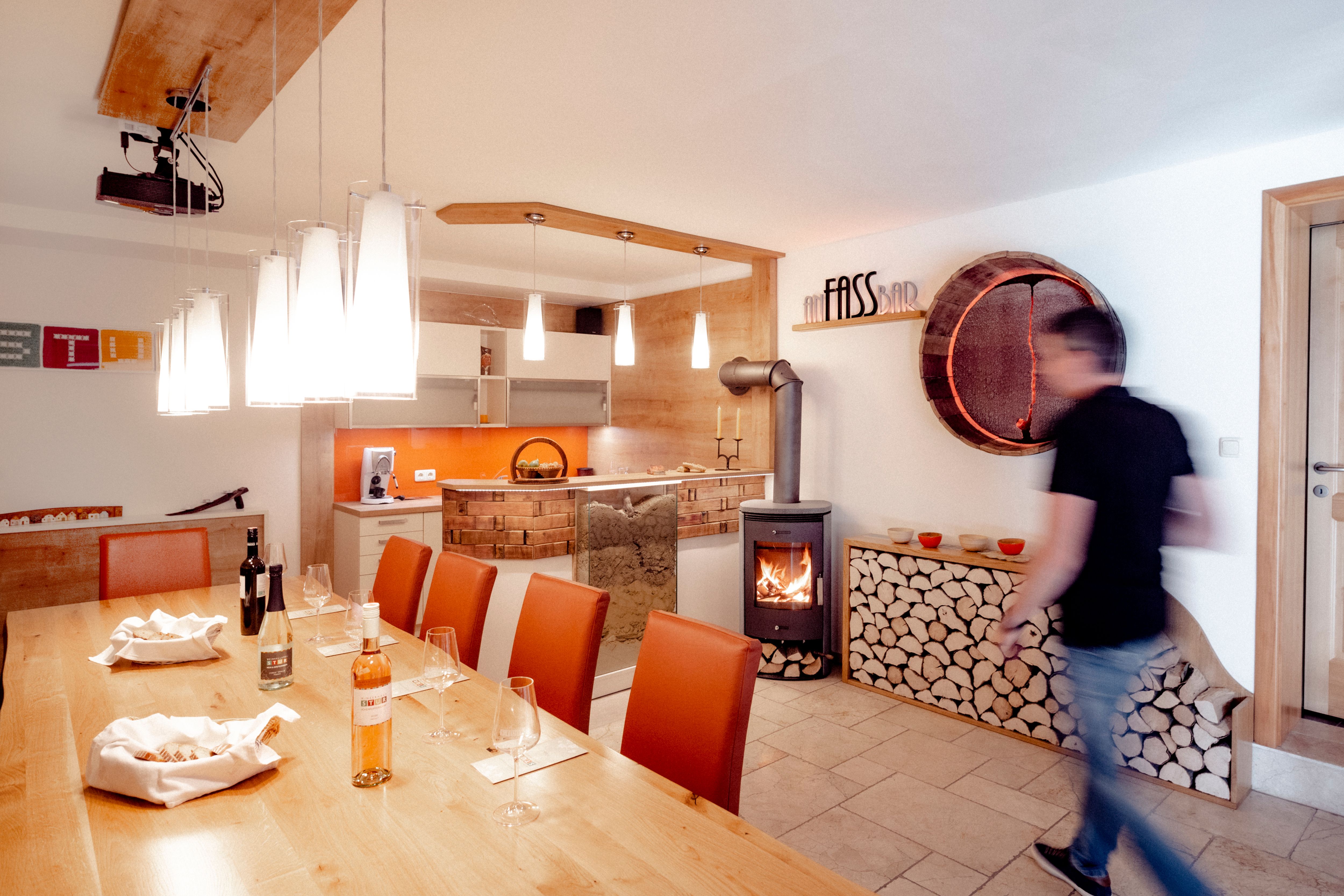 Kóstolóterem fa asztallal, borospoharakkal, kandallóval és modern világítással.