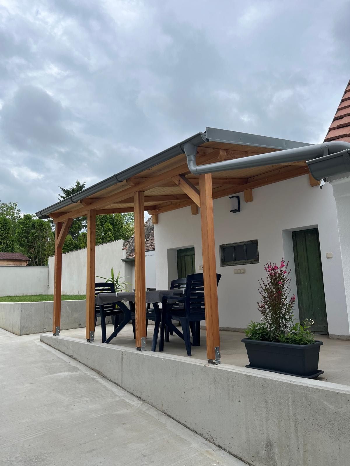 Fedett terasz asztallal és székekkel, növényekkel körülvéve.