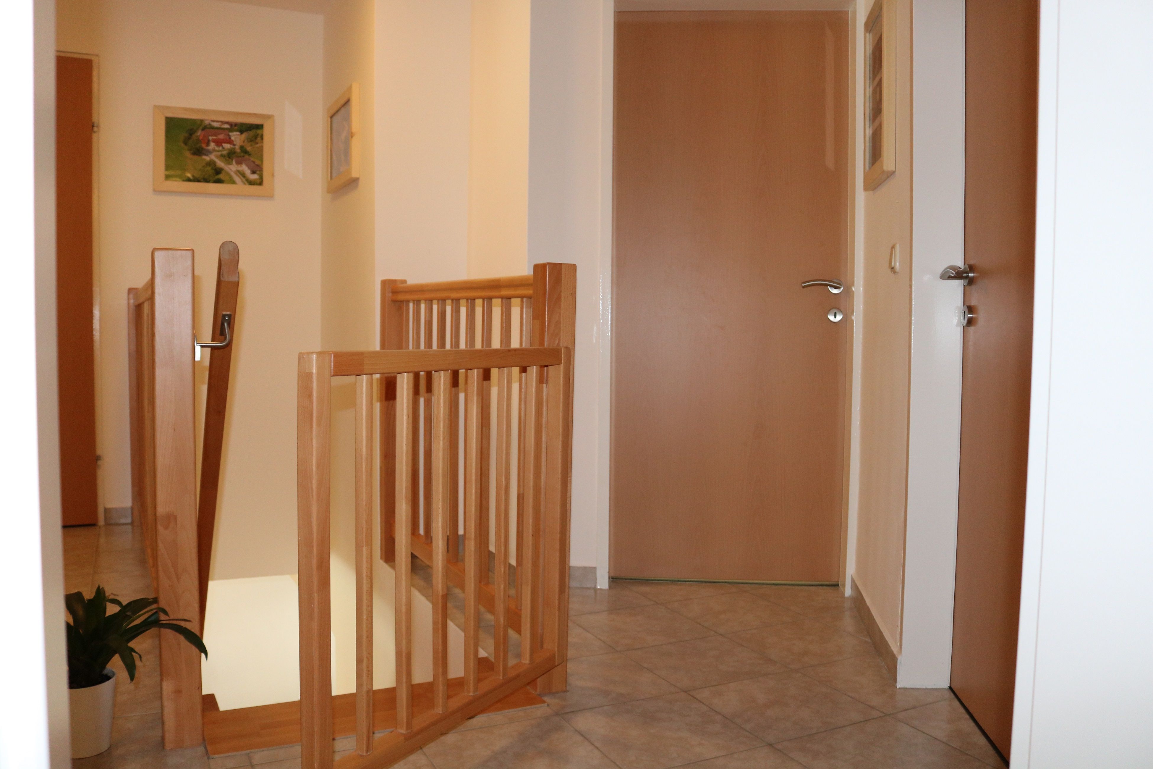 Belső nézet egy folyosóról, fa ajtókkal és korlátokkal.