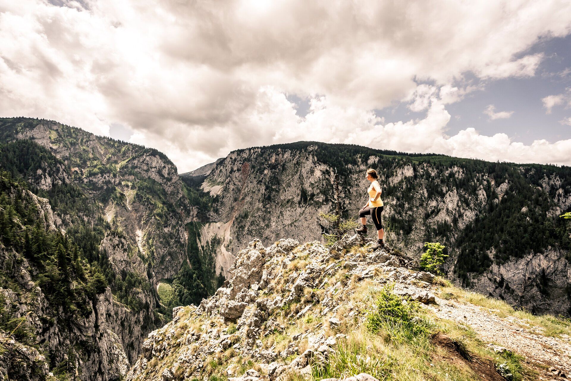 Die majestätischen Berge erheben sich stolz über das Höllental, während die Wolken sanft über den Himmel ziehen. Ein Wanderer genießt den atemberaubenden Ausblick auf die unberührte Natur und die tiefen Schluchten, die diese Region so einzigartig machen.