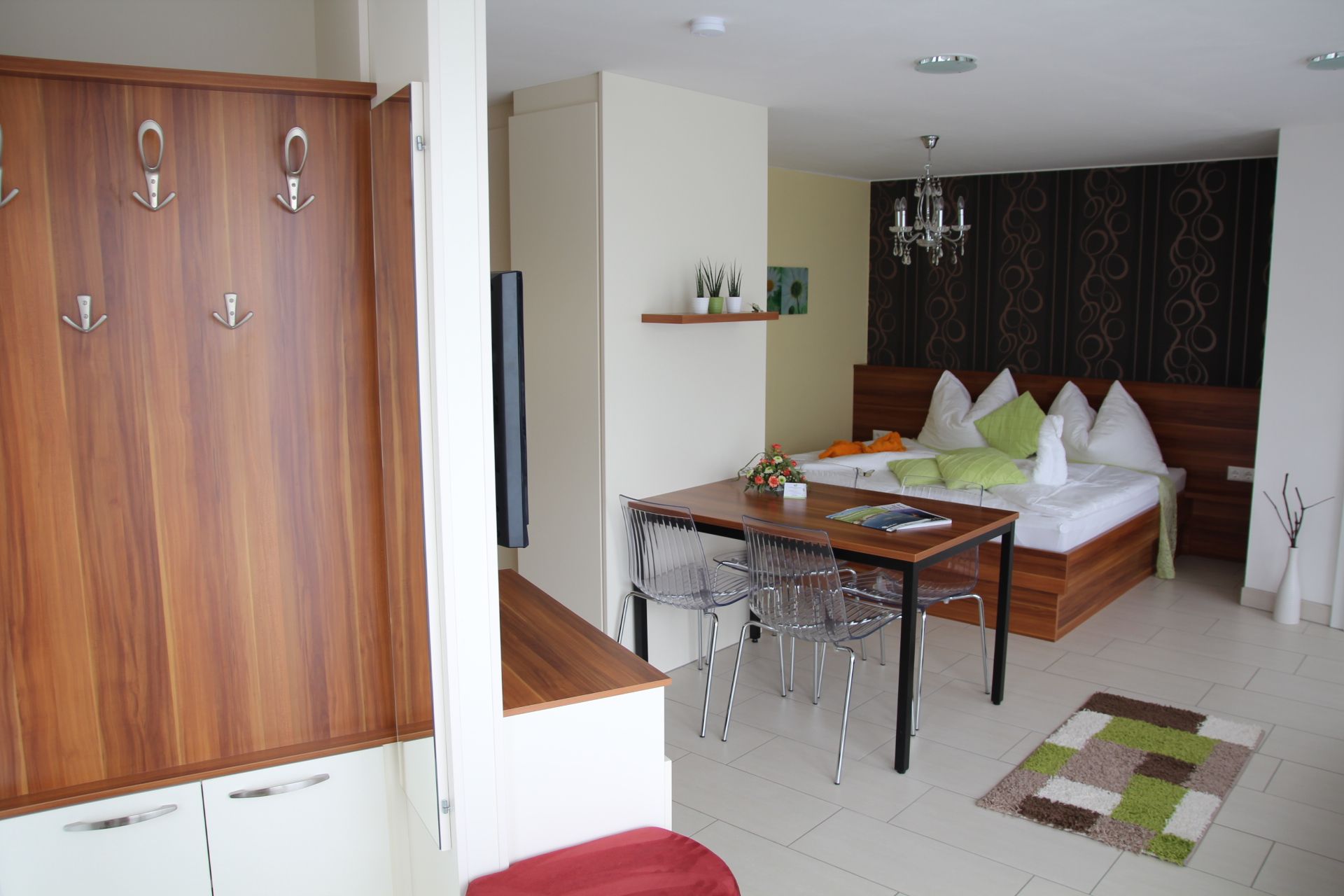 Modern lakás fabútorokkal, étkezőasztallal, ággyal és dekorációs elemekkel.