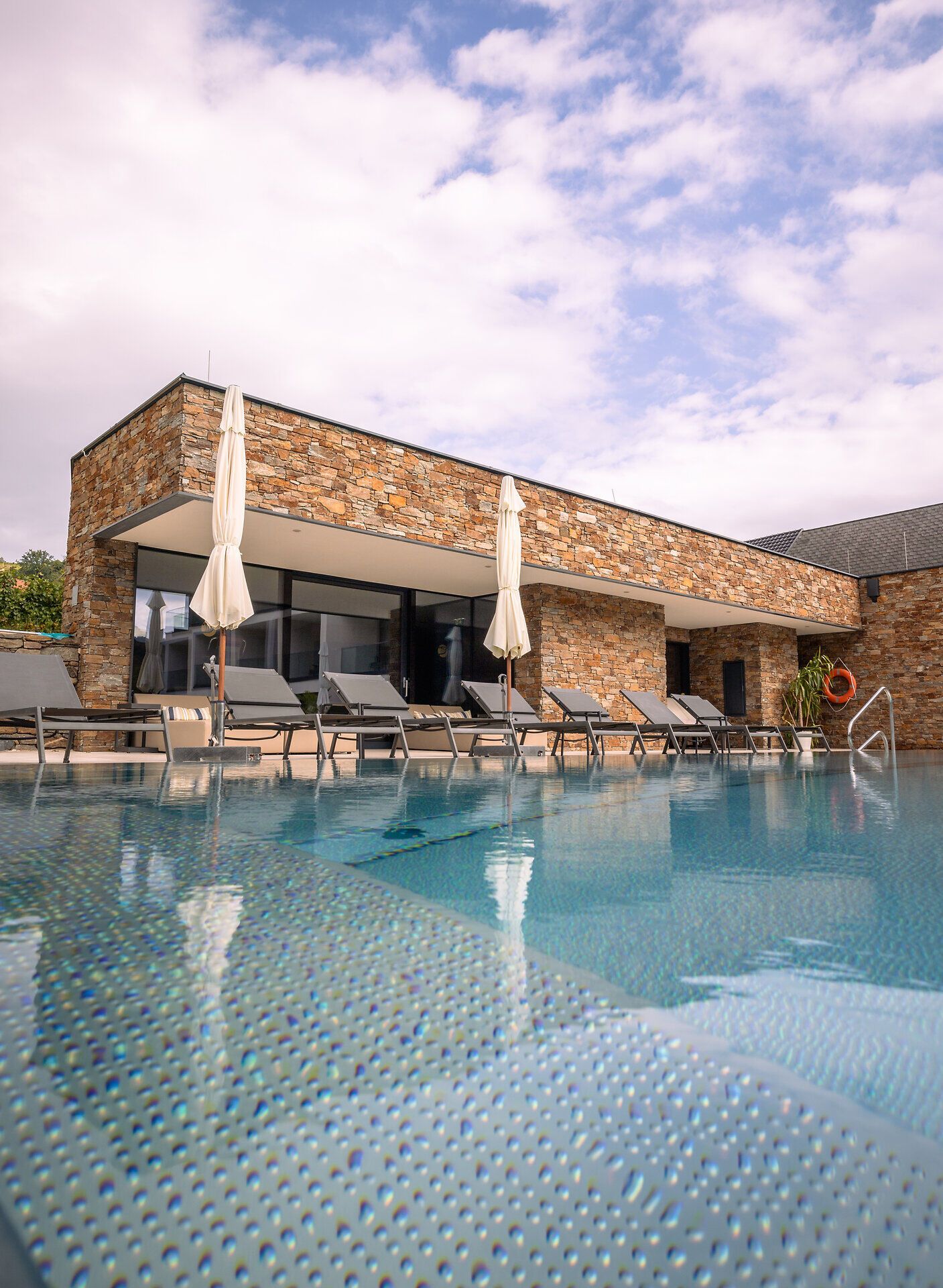 Egy modern szálloda külső nézete medencével és nyugágyakkal.