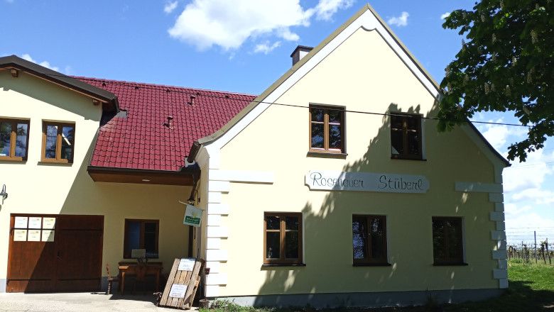 Sárga épület piros tetővel és a "Rosenauer Stüberl" felirattal.