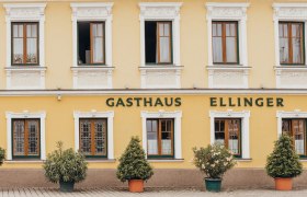 Egy sárga színű vendéglő homlokzata "Gasthaus Ellinger" felirattal.