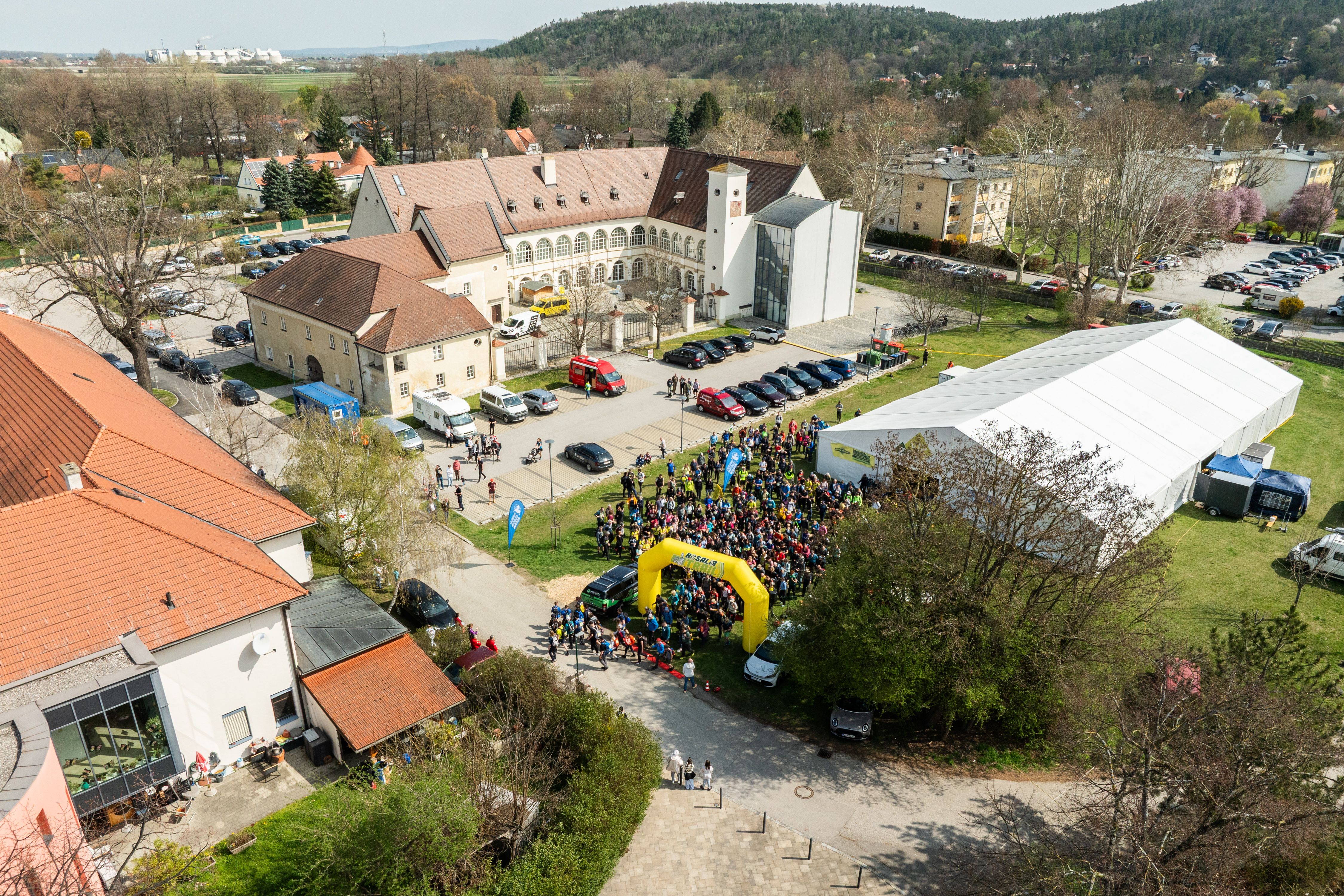 Légi felvétel egy kastélyról, emberek, sátrak és épületek tömkelegével a Rosalia Trail Challenge során.
