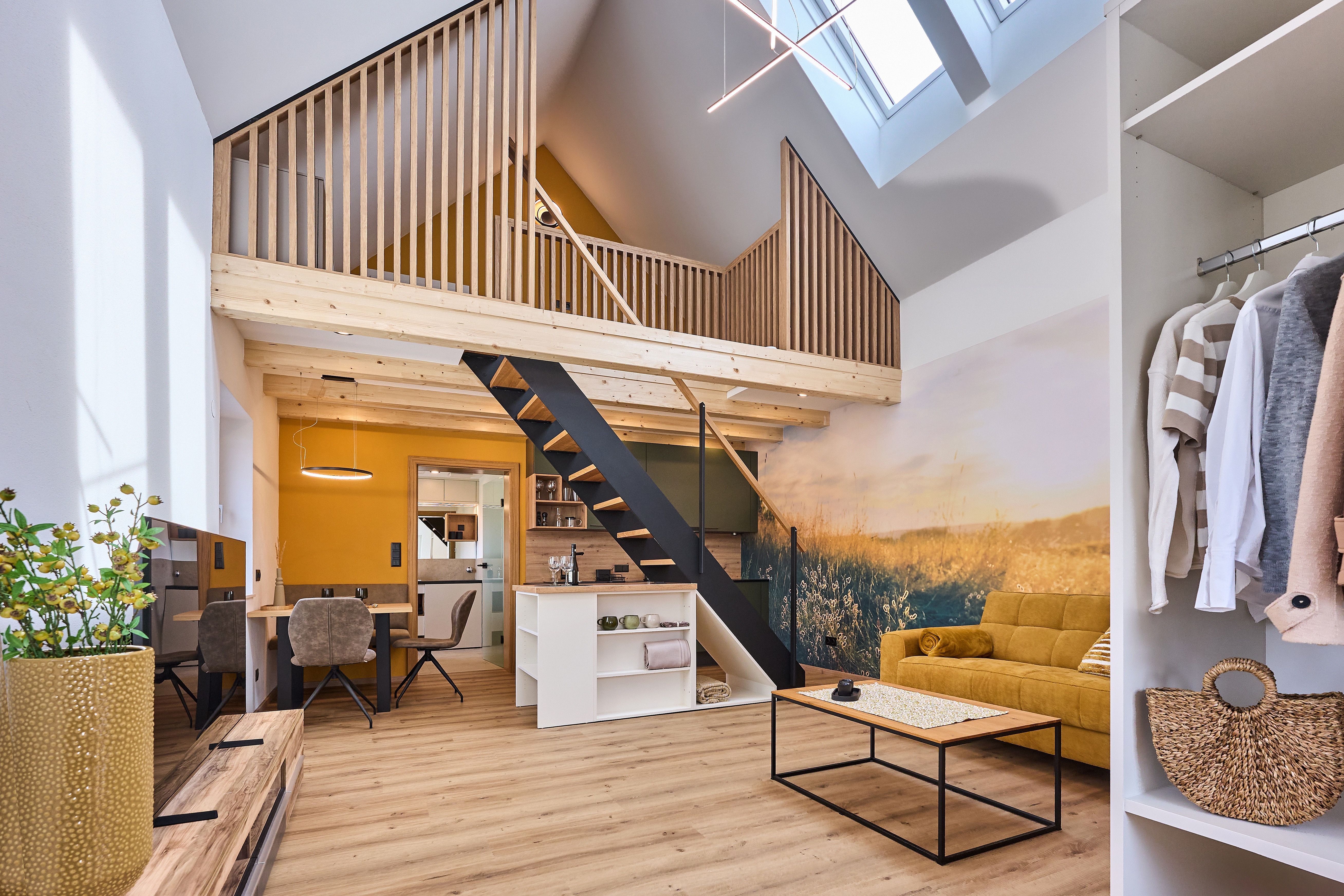 Modern loft nyitott galériával, sárga kanapéval és fa elemekkel.