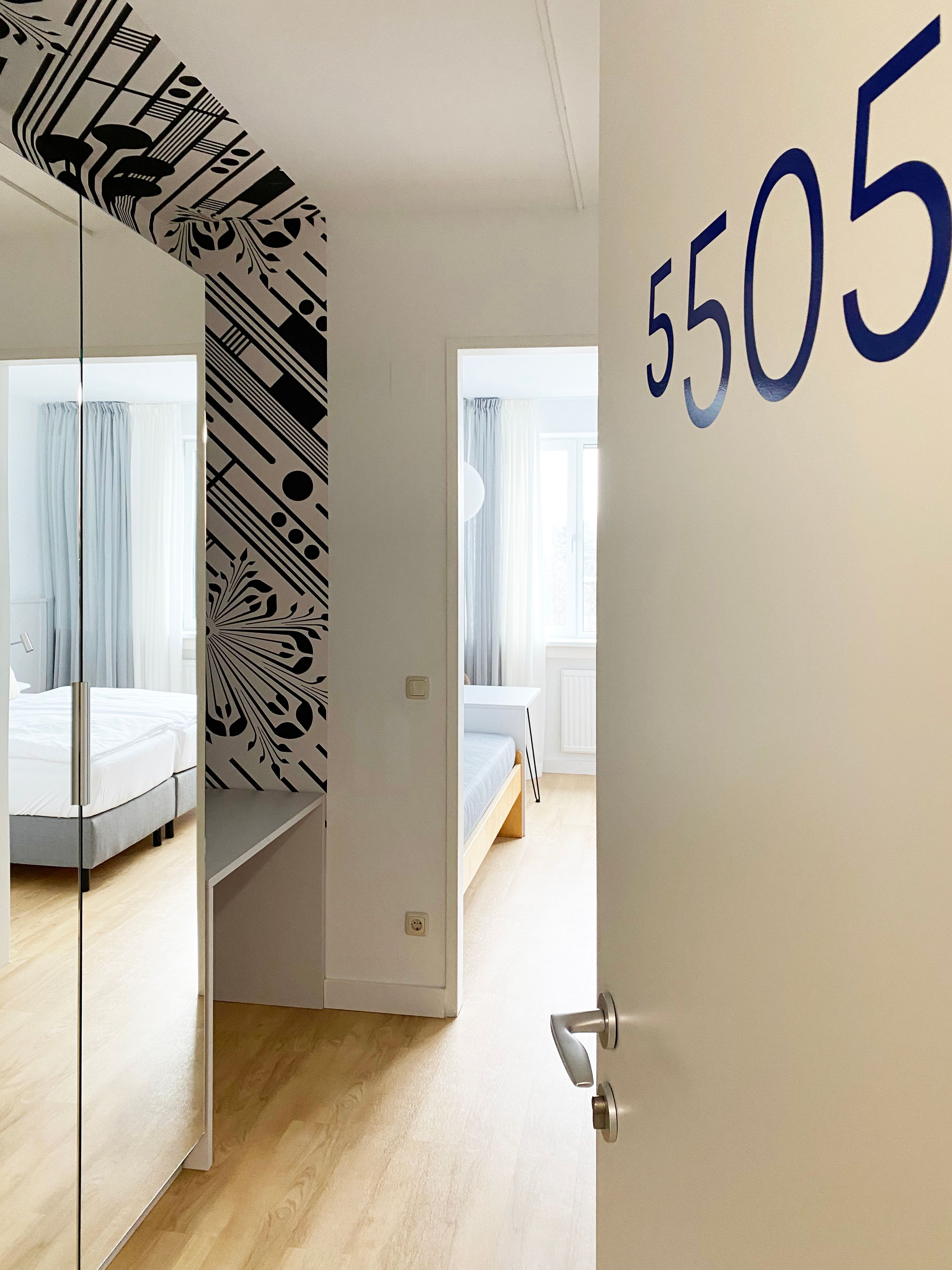 Az 5505-ös számú, modern berendezésű, ágyas, tükrös vendégszoba látképe.